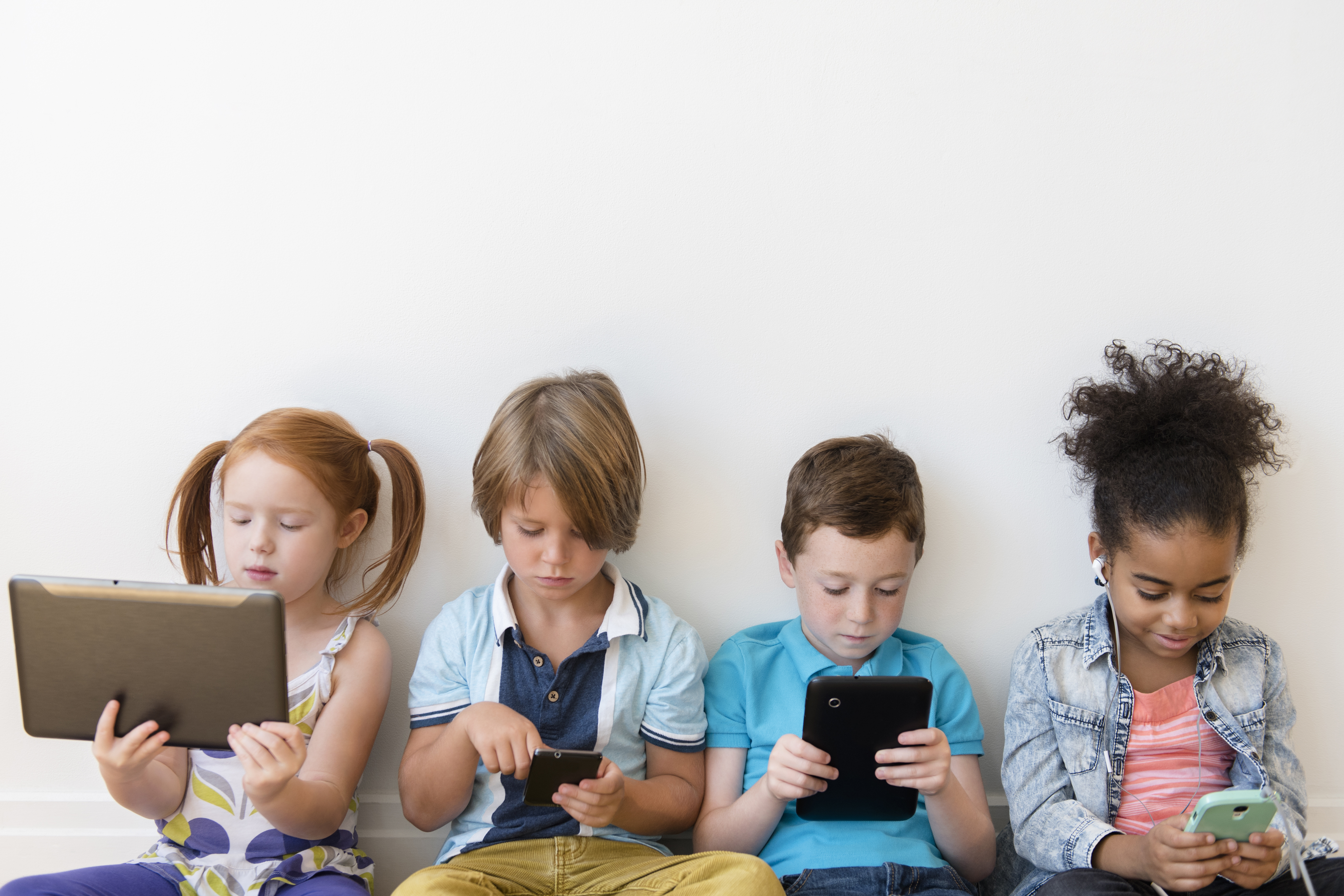 Image of four children using tablets and smartphones.