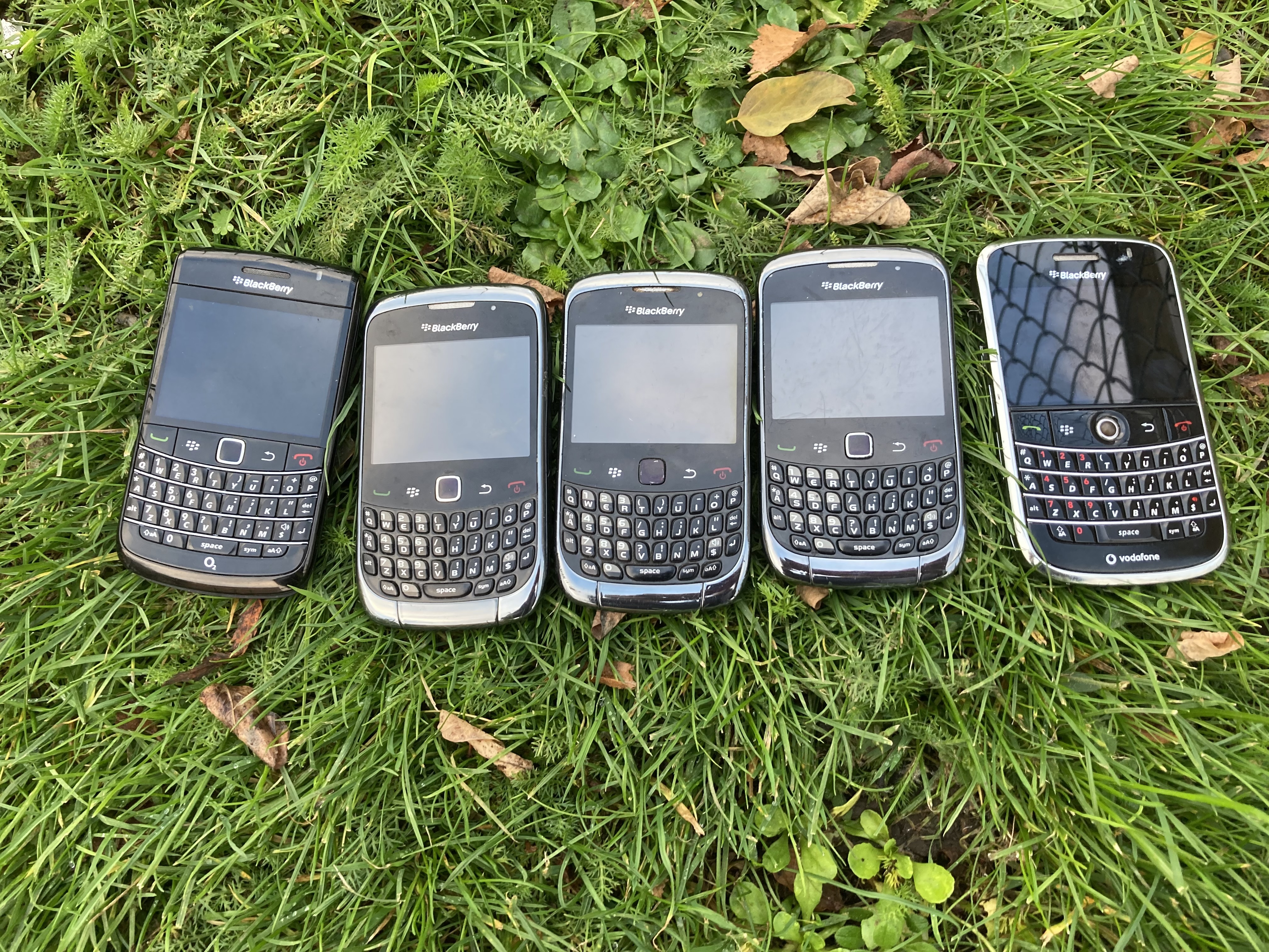 five blackberry phones sitting on the lawn