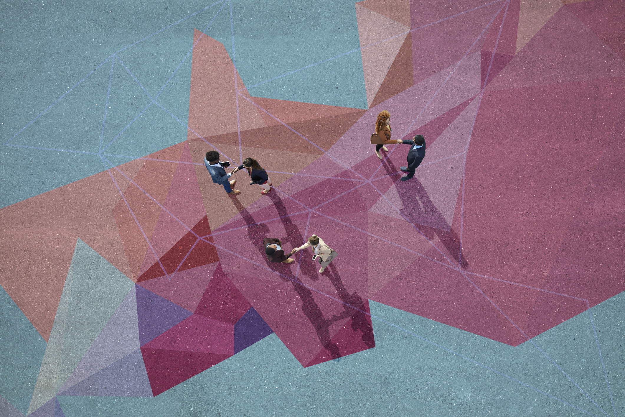 Group of young adults, photographed from above, on various painted tarmac surface shaking hands to close a deal.