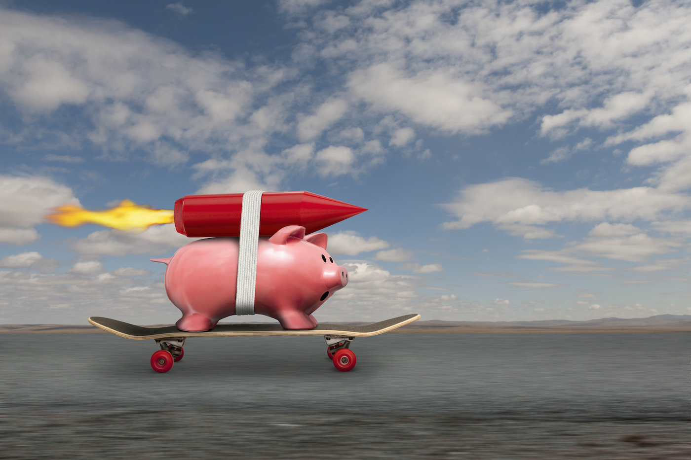 A piggy bank streaks down the road to riches on a skateboard and with a rocket strapped to his back.