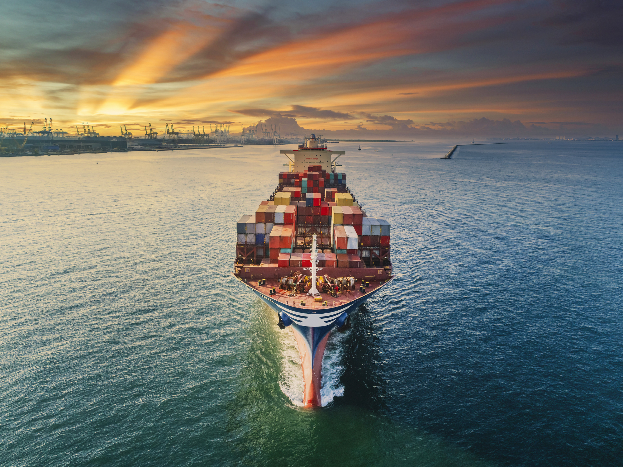 Aerial front view Container cargo ship full carrier container with terminal commercial port background for business logistics, import export, shipping or freight transportation.