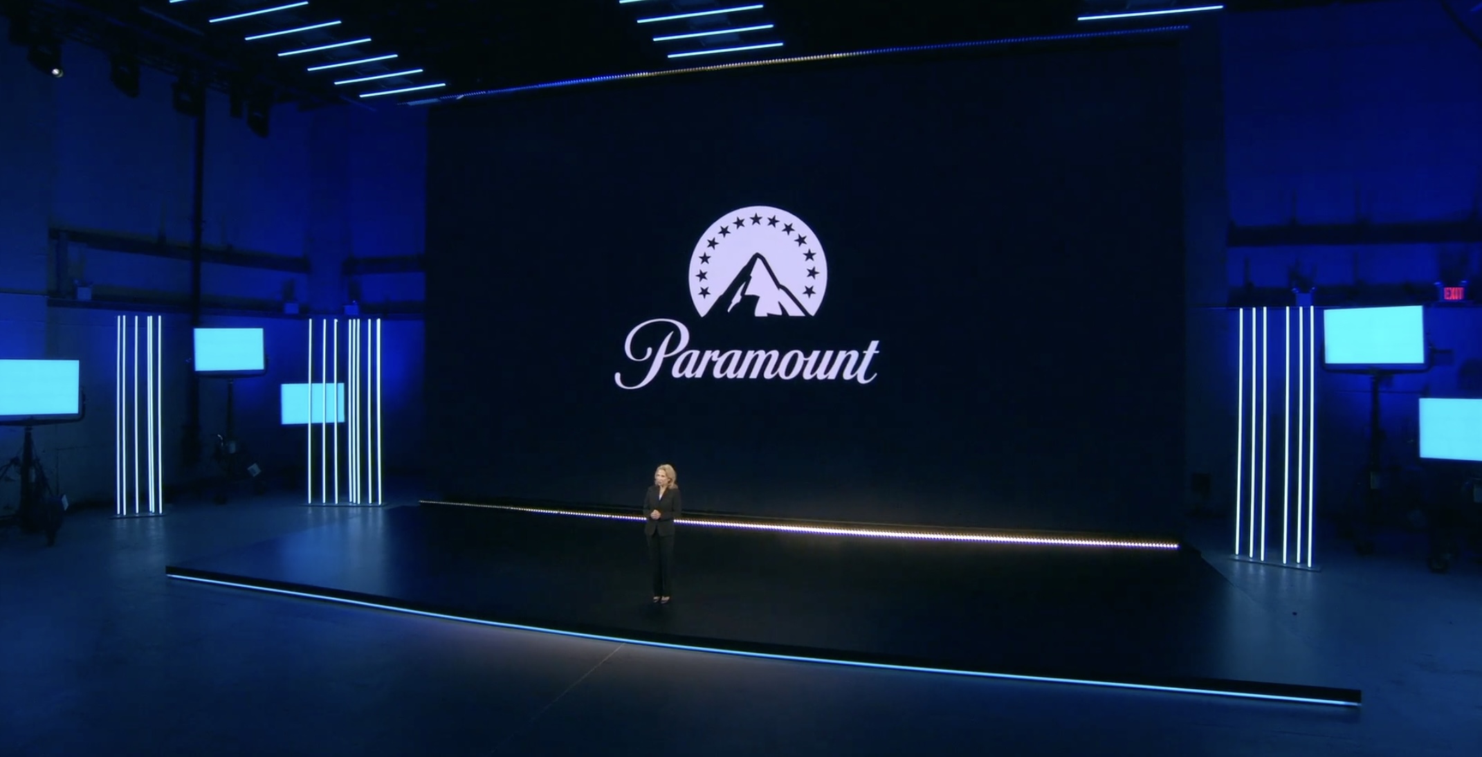 Woman speaking onstage in front of screen with large Paramount logo