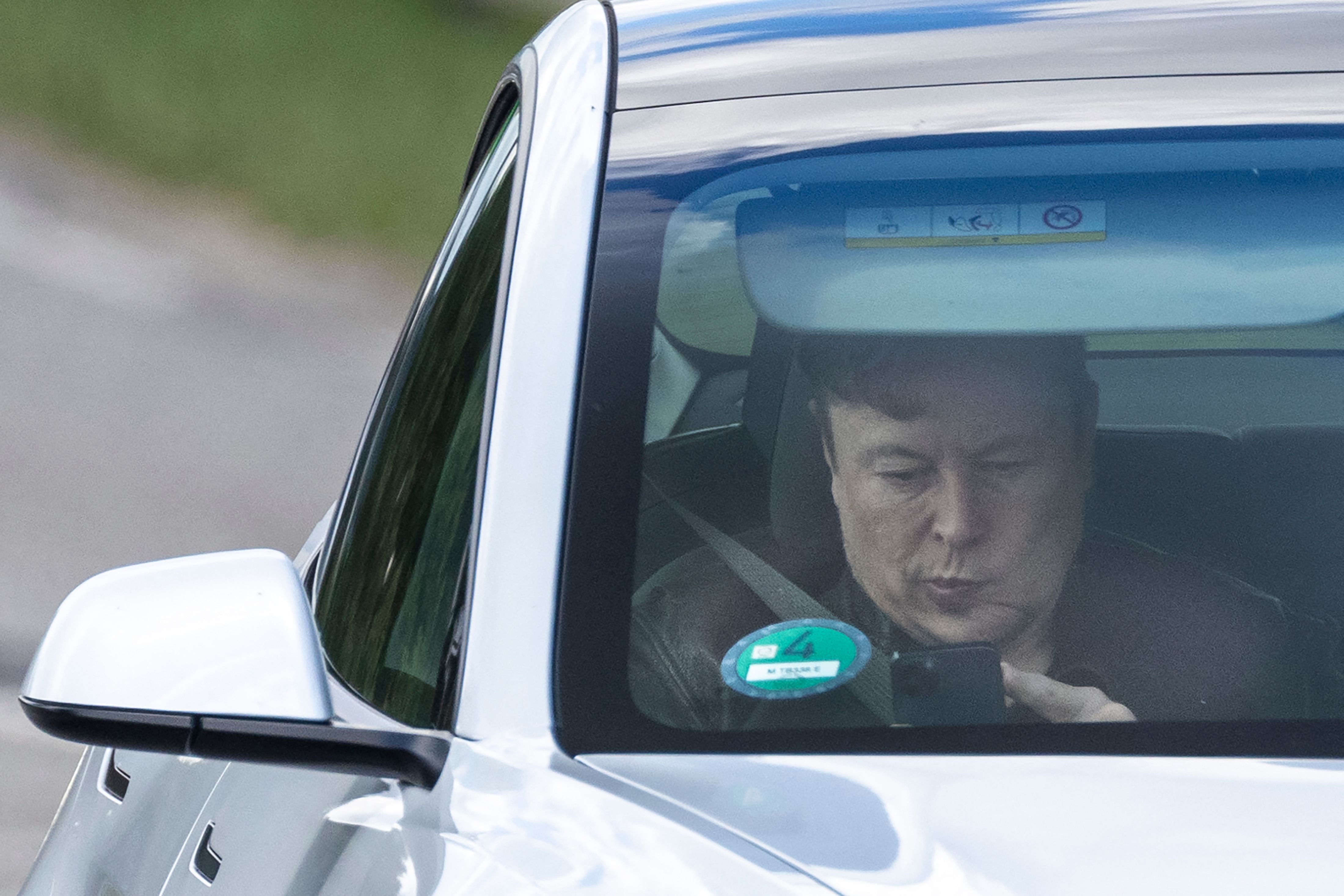 Tesla CEO Elon Musk uses his mobile device as he sits in the car arriving to the construction site for the new plant, the so-called "Giga Factory", of US electric carmaker Tesla in Gruenheide near Berlin, northeastern Germany