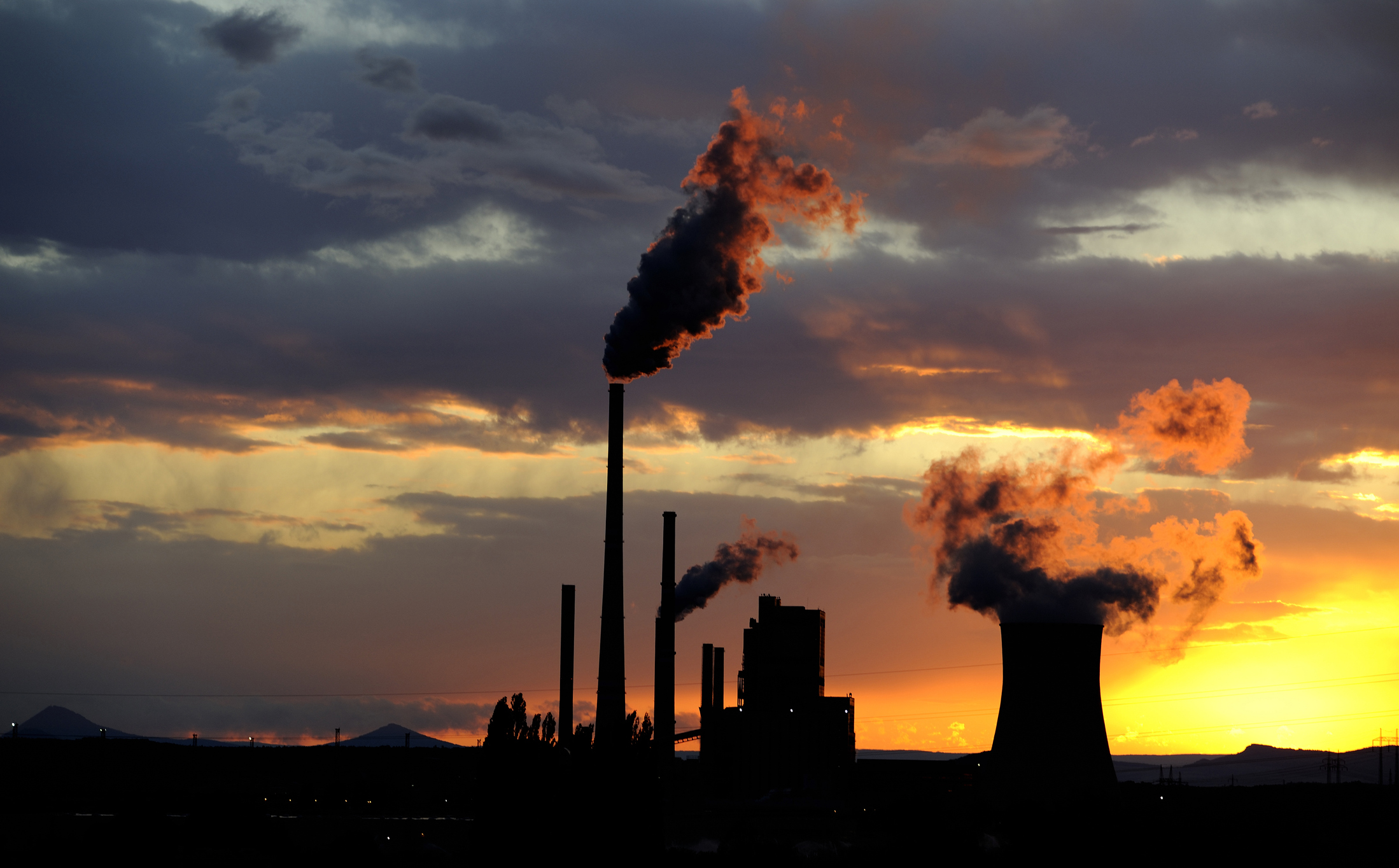 Coal power station with smoking chimneys in sunset with cloudy sky, industrial landscape