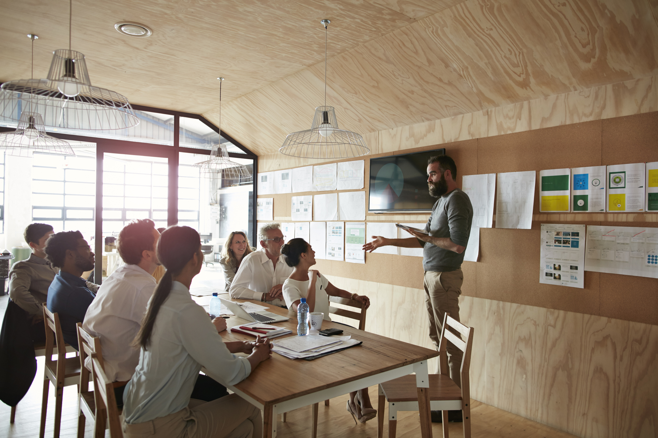 Team working on an application design plan in a conference room with lots of examples hanging from the walls.