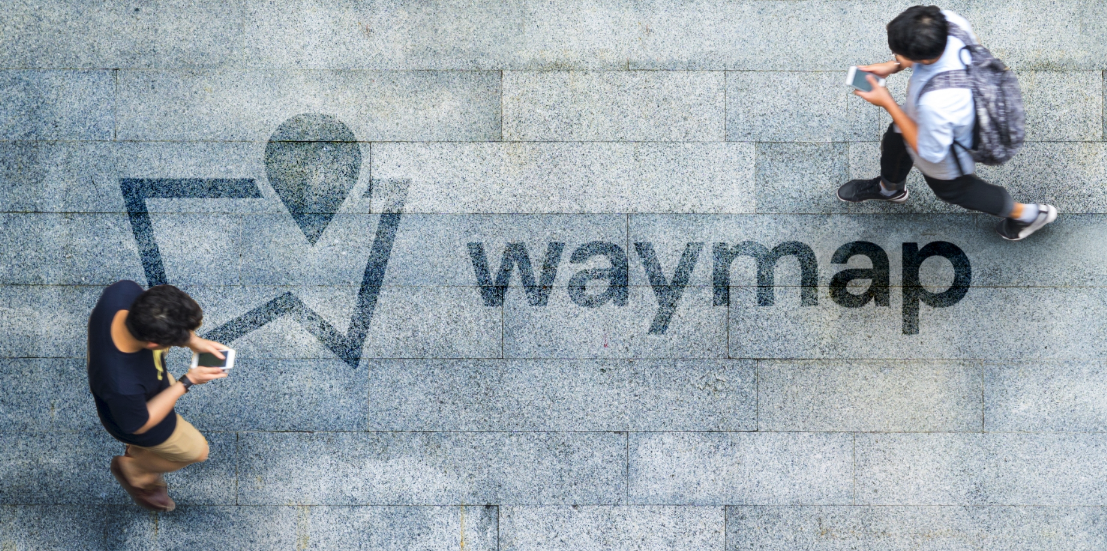 Waymap logo on ground as two men walk by using smartphones