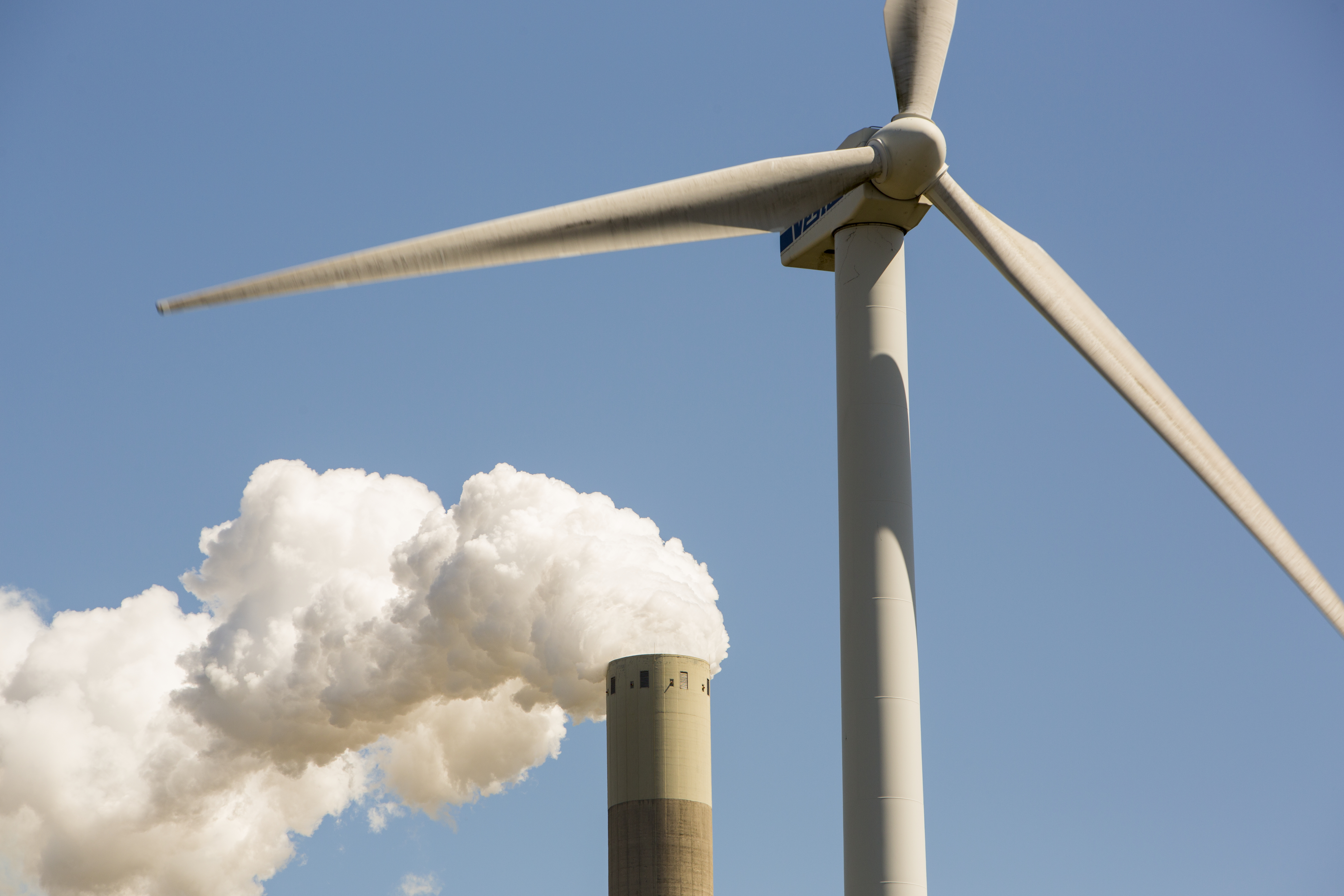 Wind turbine and smokestack with pollution illustrates how US will fall behind Europe and China after Supreme Court EPA ruling
