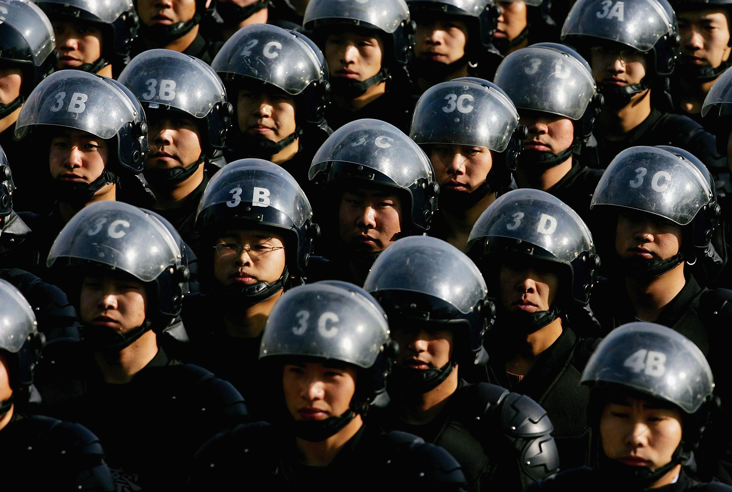 A group of Chinese police officers with helmets and riot gear.