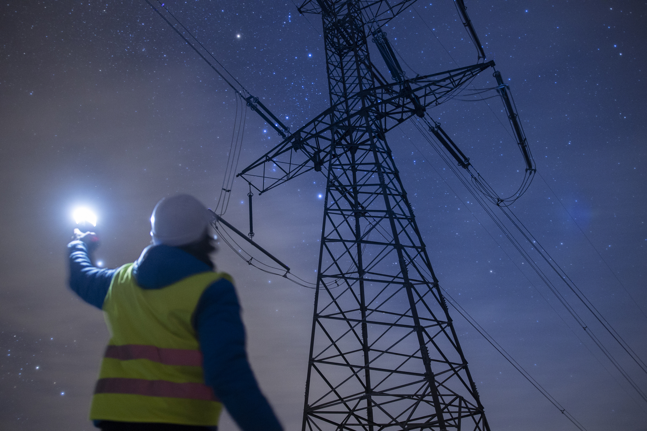 High-voltage engineer working on power lines at night.