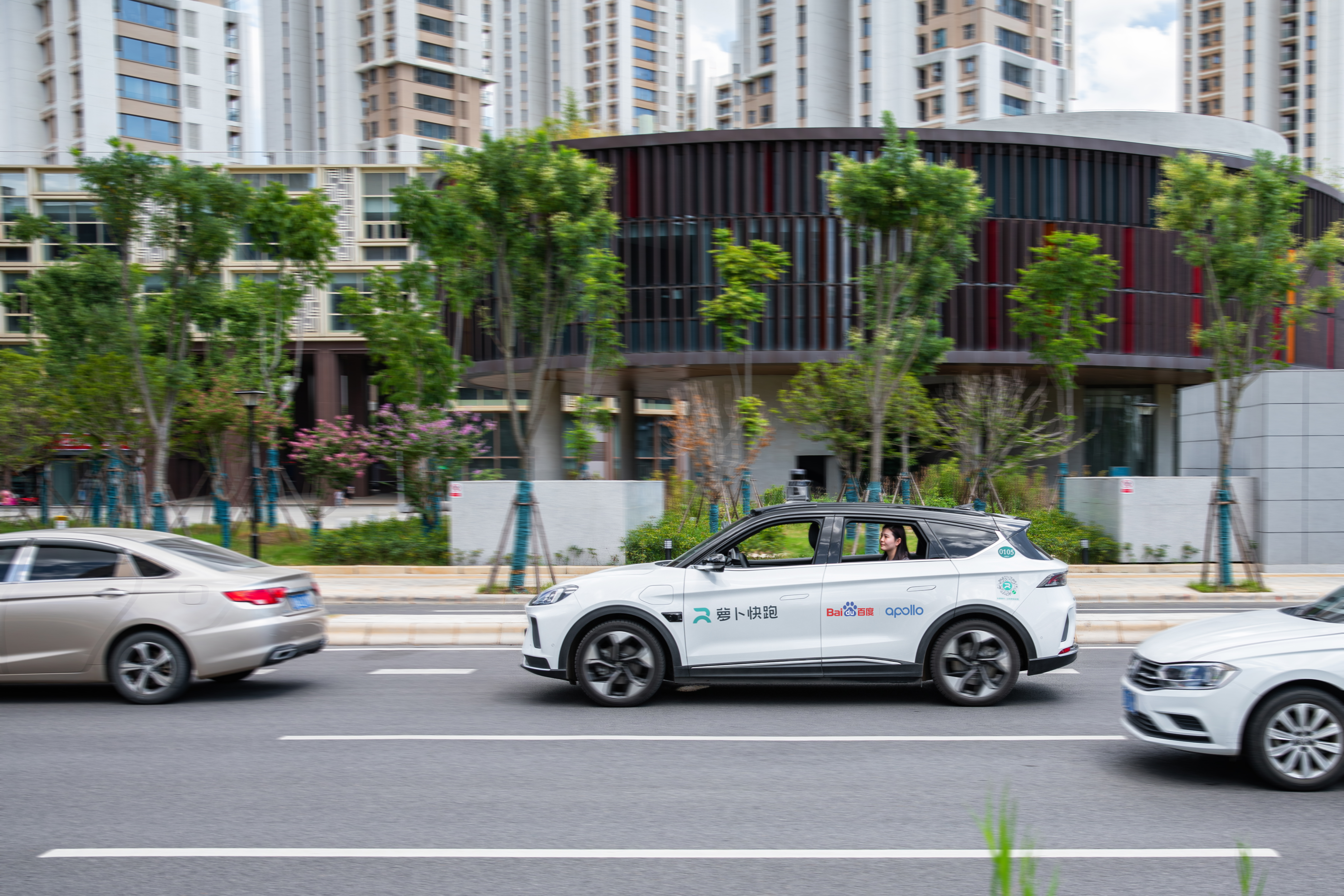 a whilte autonomous vehicle on a city street, with apollo branding