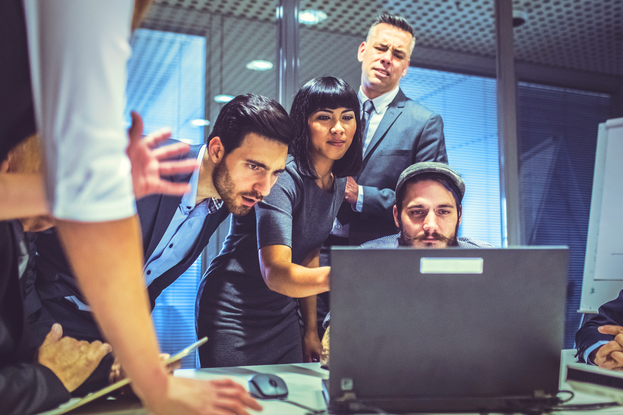Group of people gathered around a computer during a business crisis.