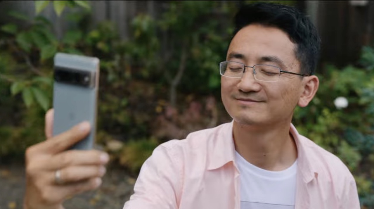 A man holds a Google Pixel 7 phone up to take a selfie. His eyes are closed.