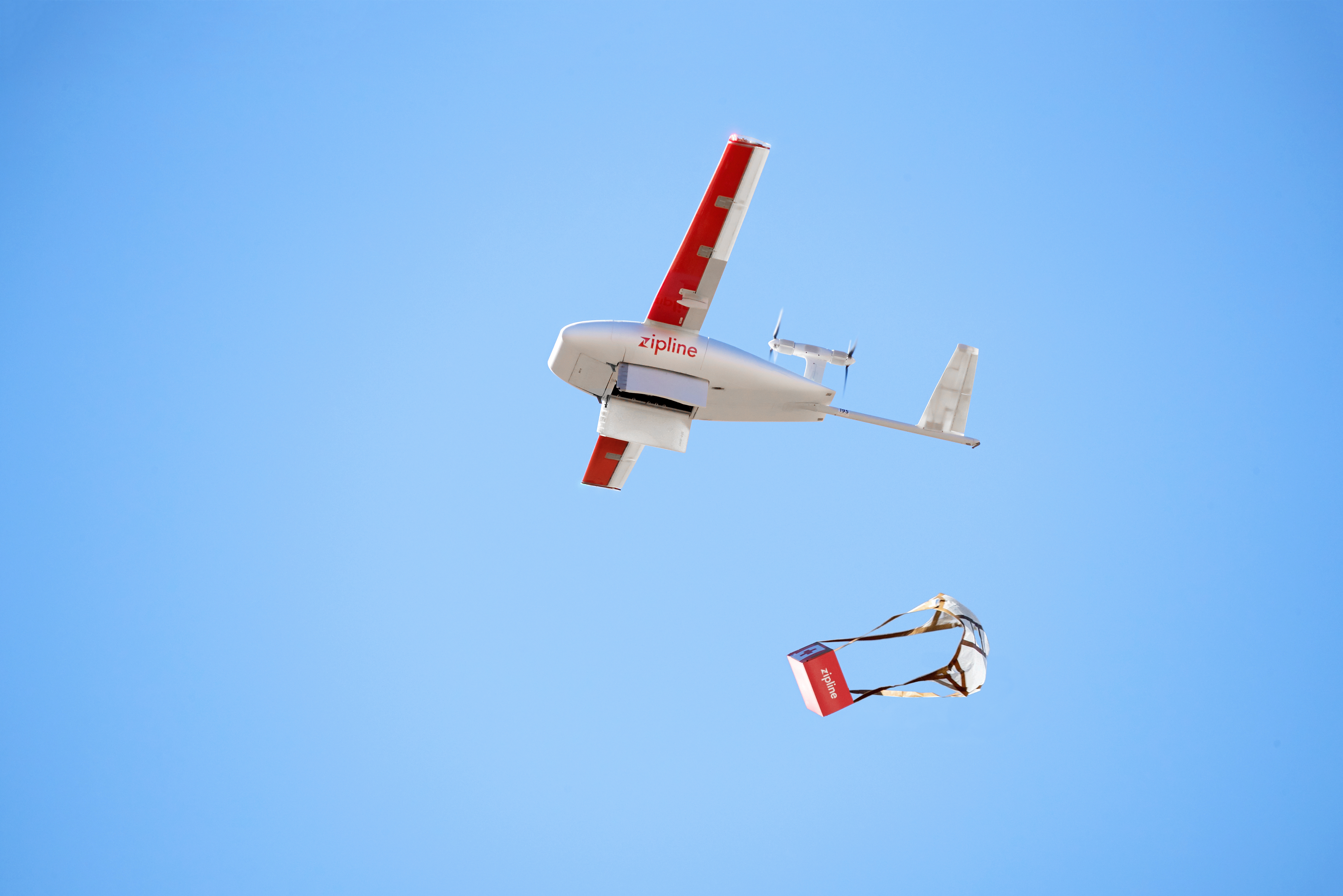 A Zipline drone drops a parachuted package out of the sky
