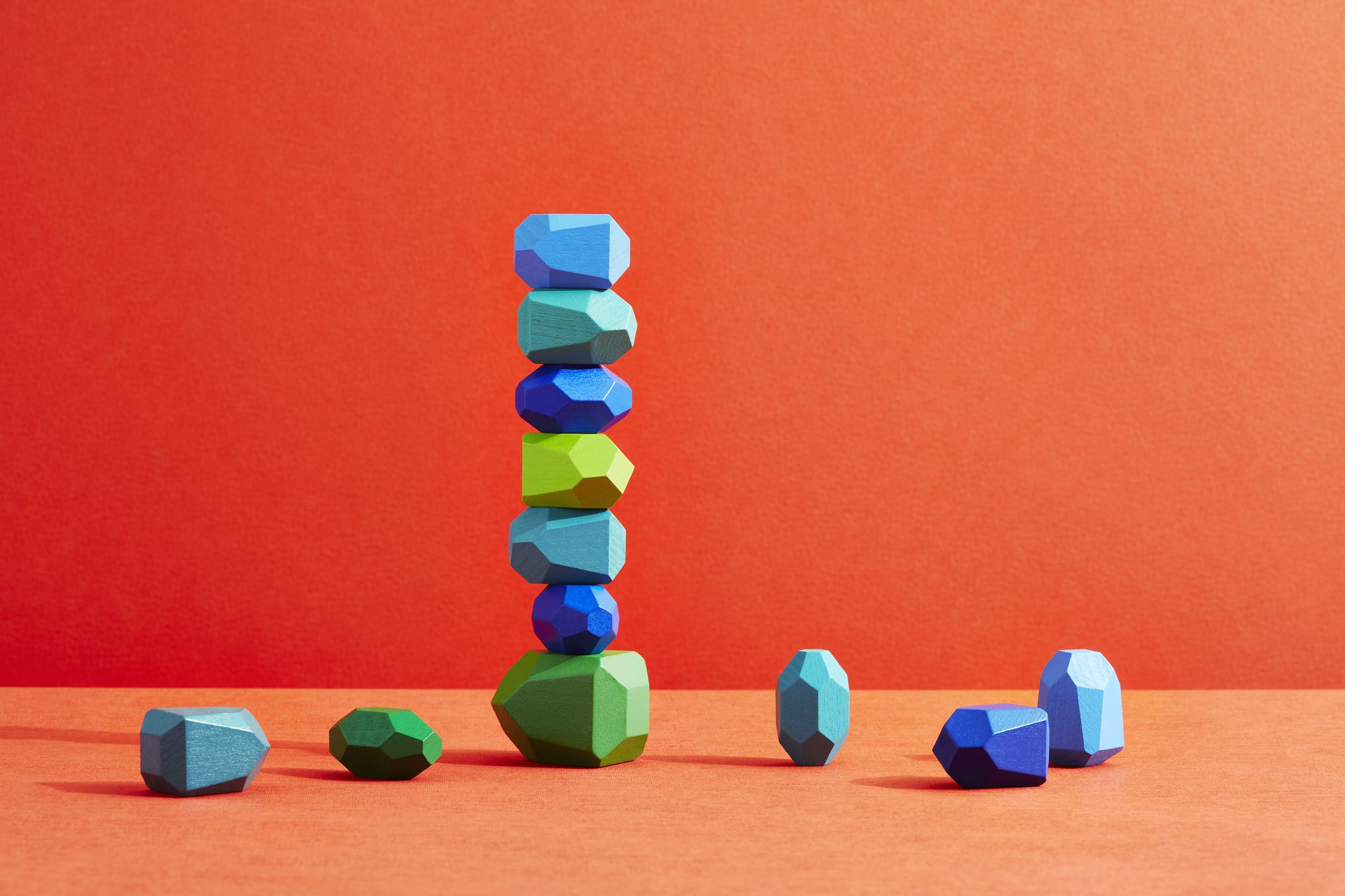 An incomplete stack of coloured pebbles on an orange background