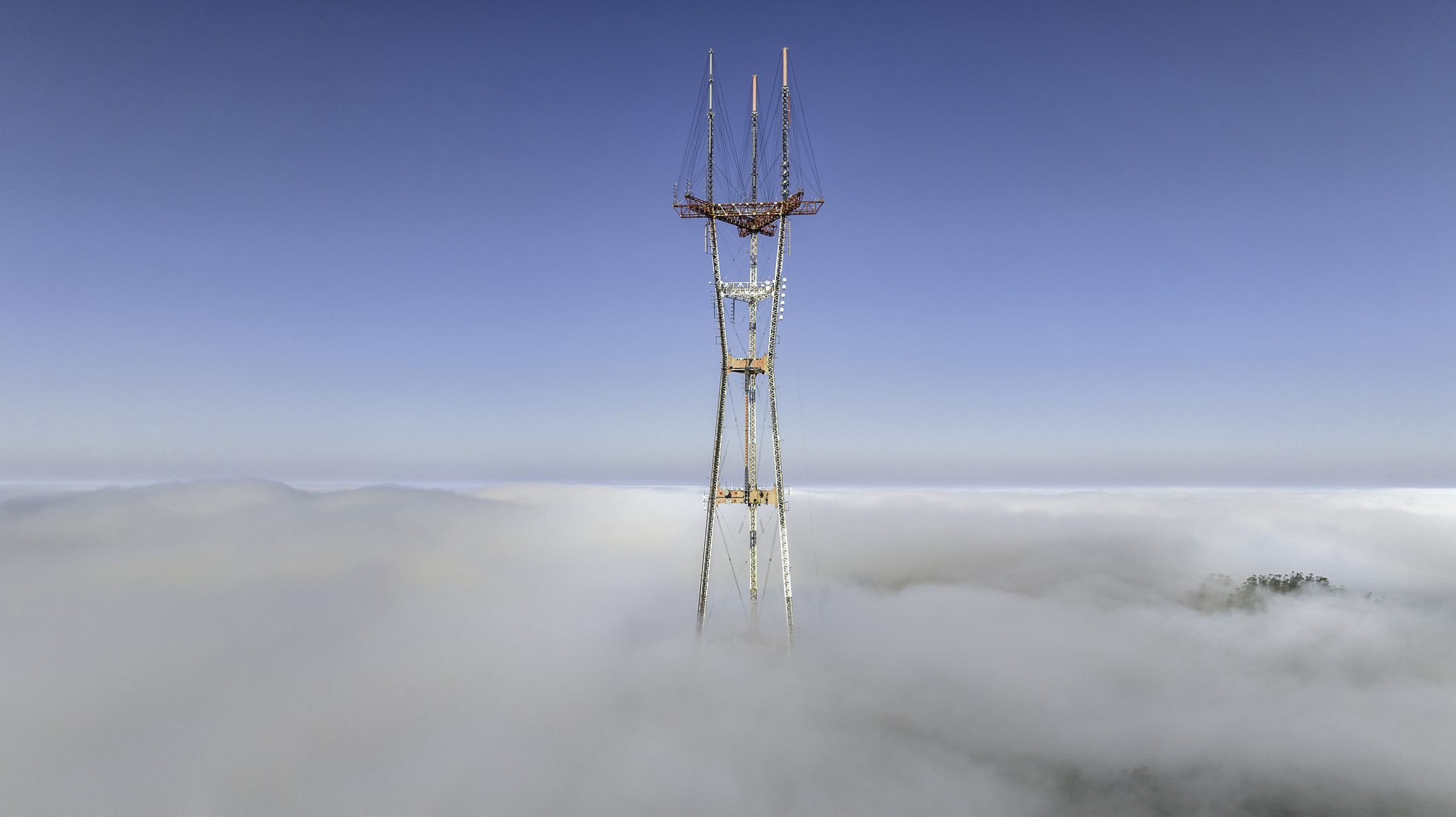 photos of a foggy Sutro Tower in San Francisco breaking through fog.