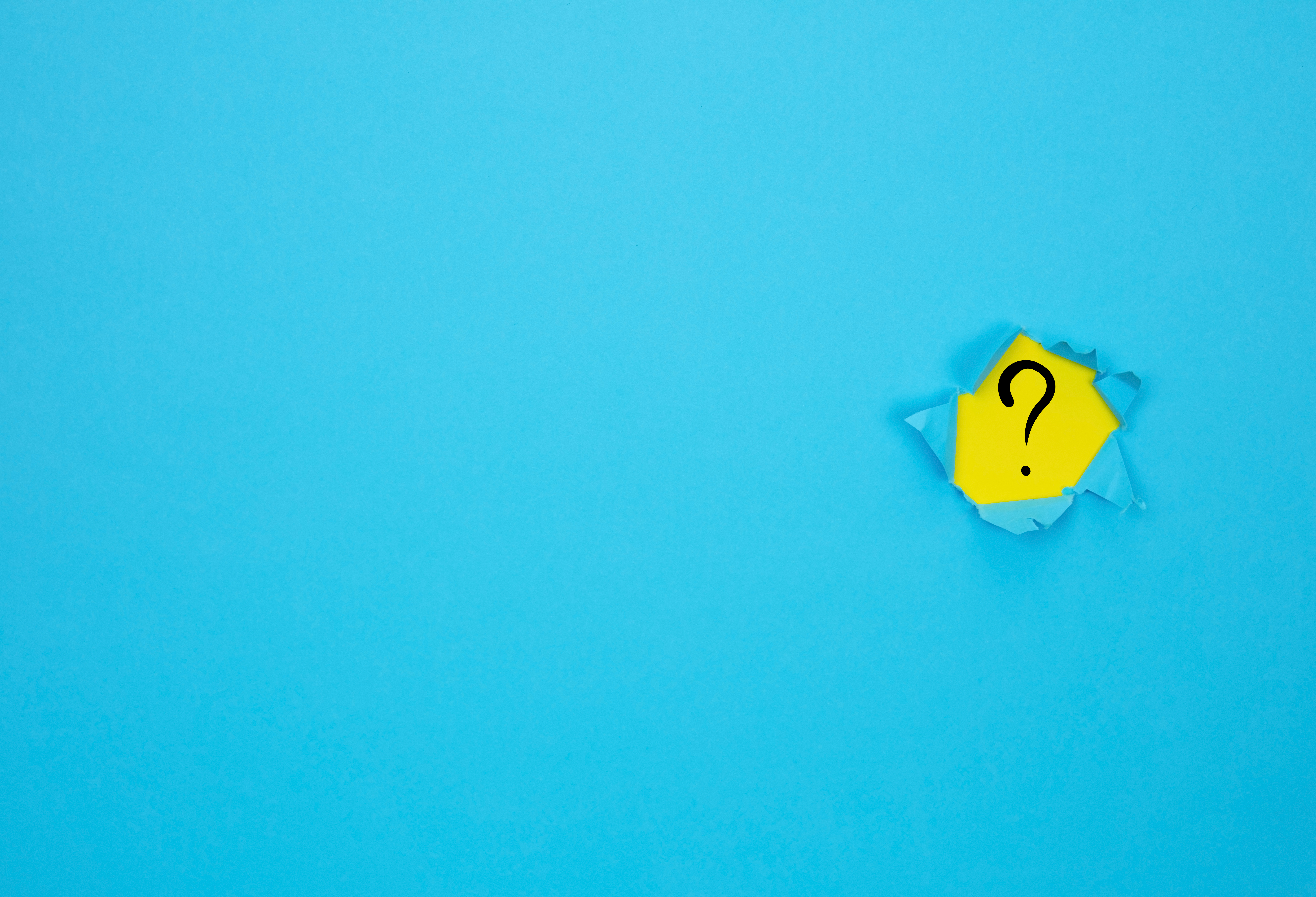 Image of a hole in a blue page revealing a question mark on a yellow background.