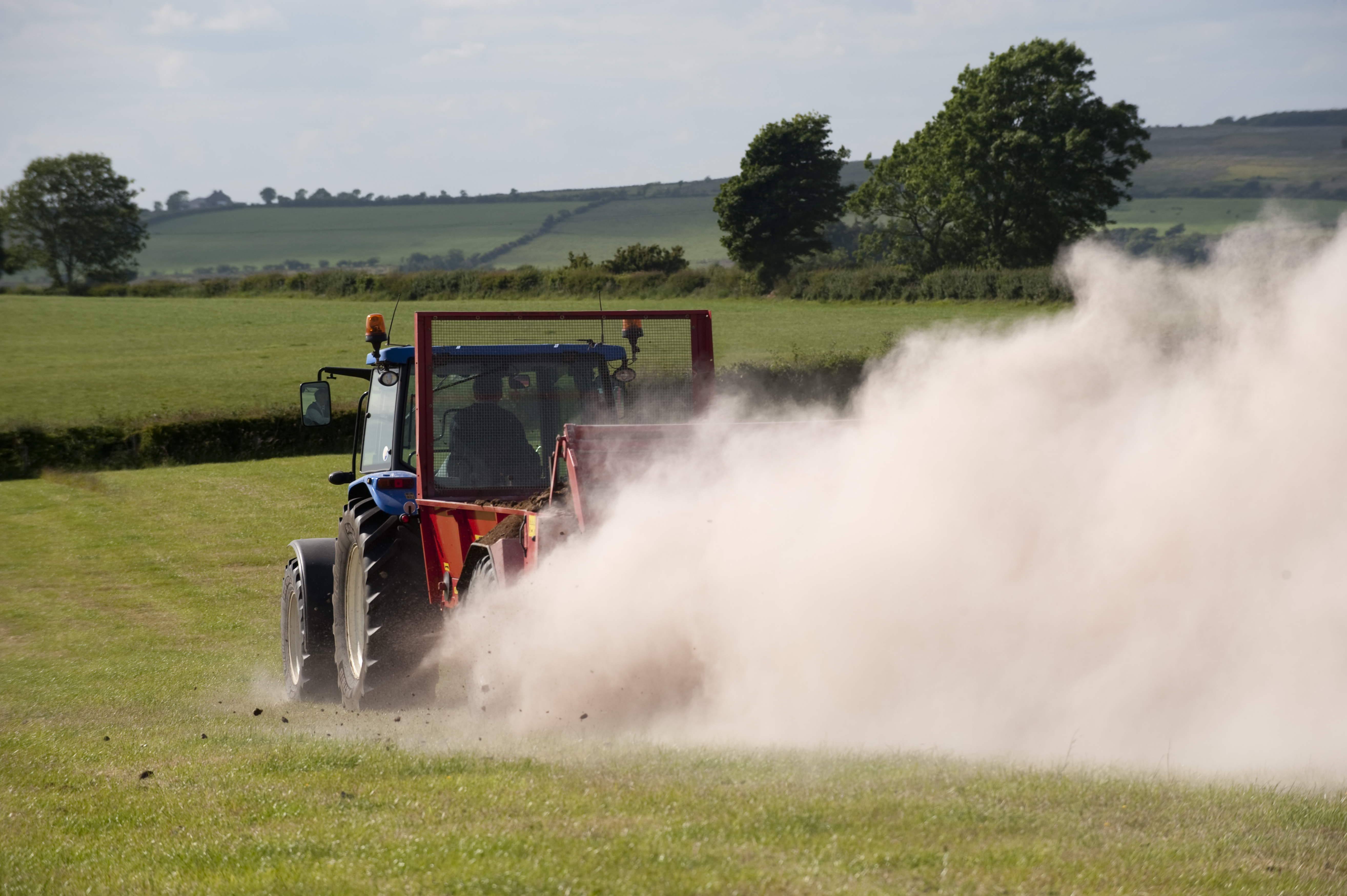 Farmer spreading chicken manure mixed with lime on newly harvested meadow