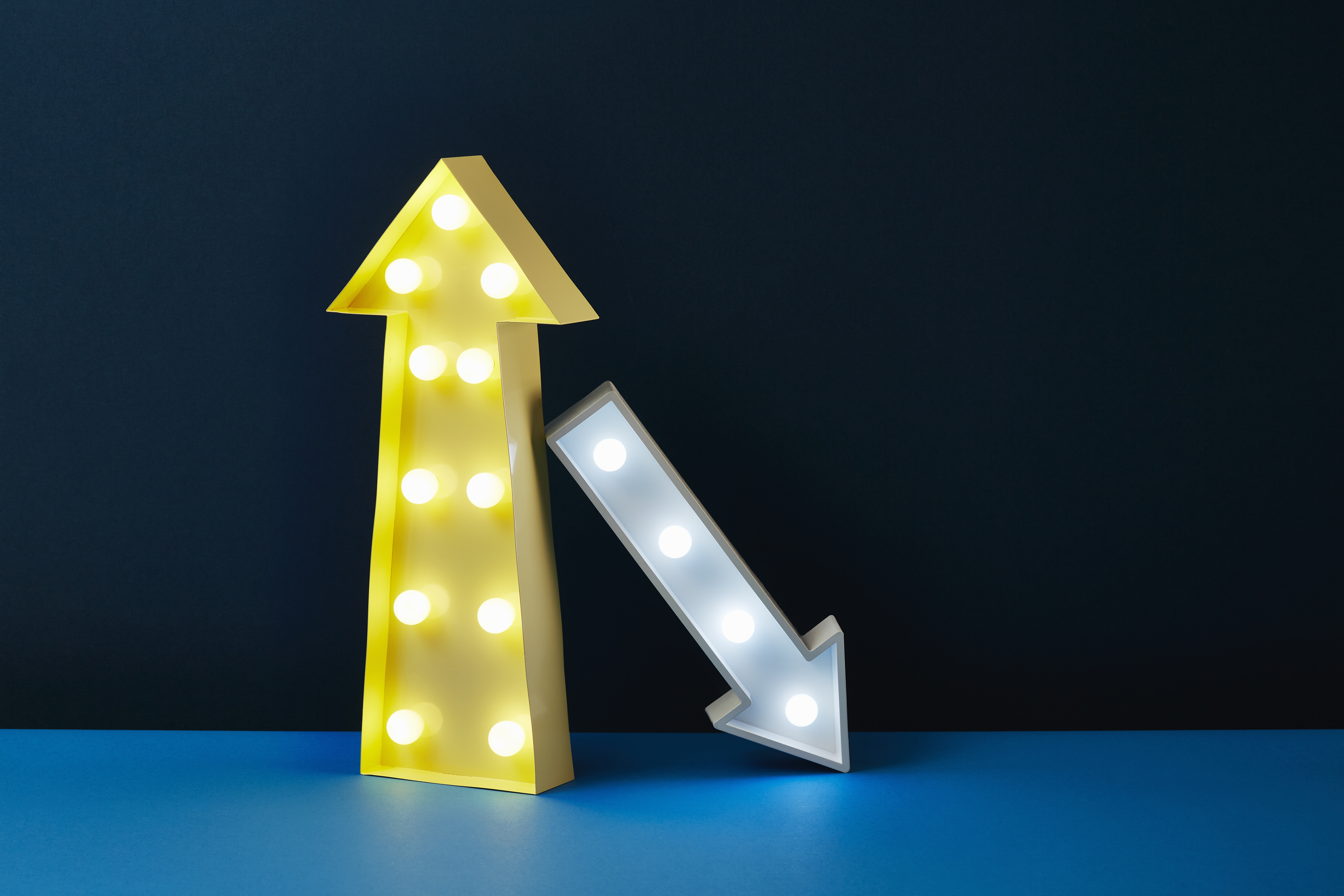 One big yellow arrow points up while a smaller white arrow leans on it and points down.