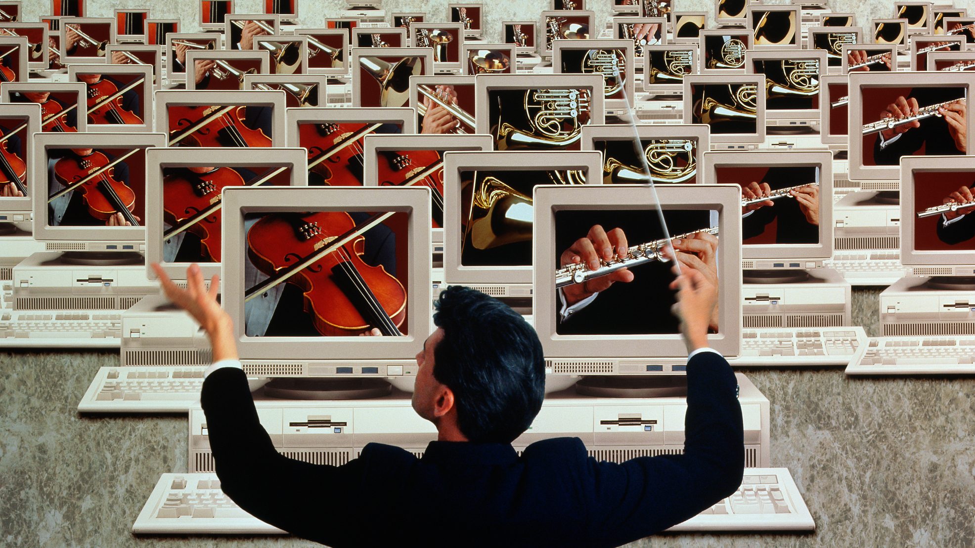 Conductor in front of 'orchestra' of computer screens, depicting 'microservices orchestration'