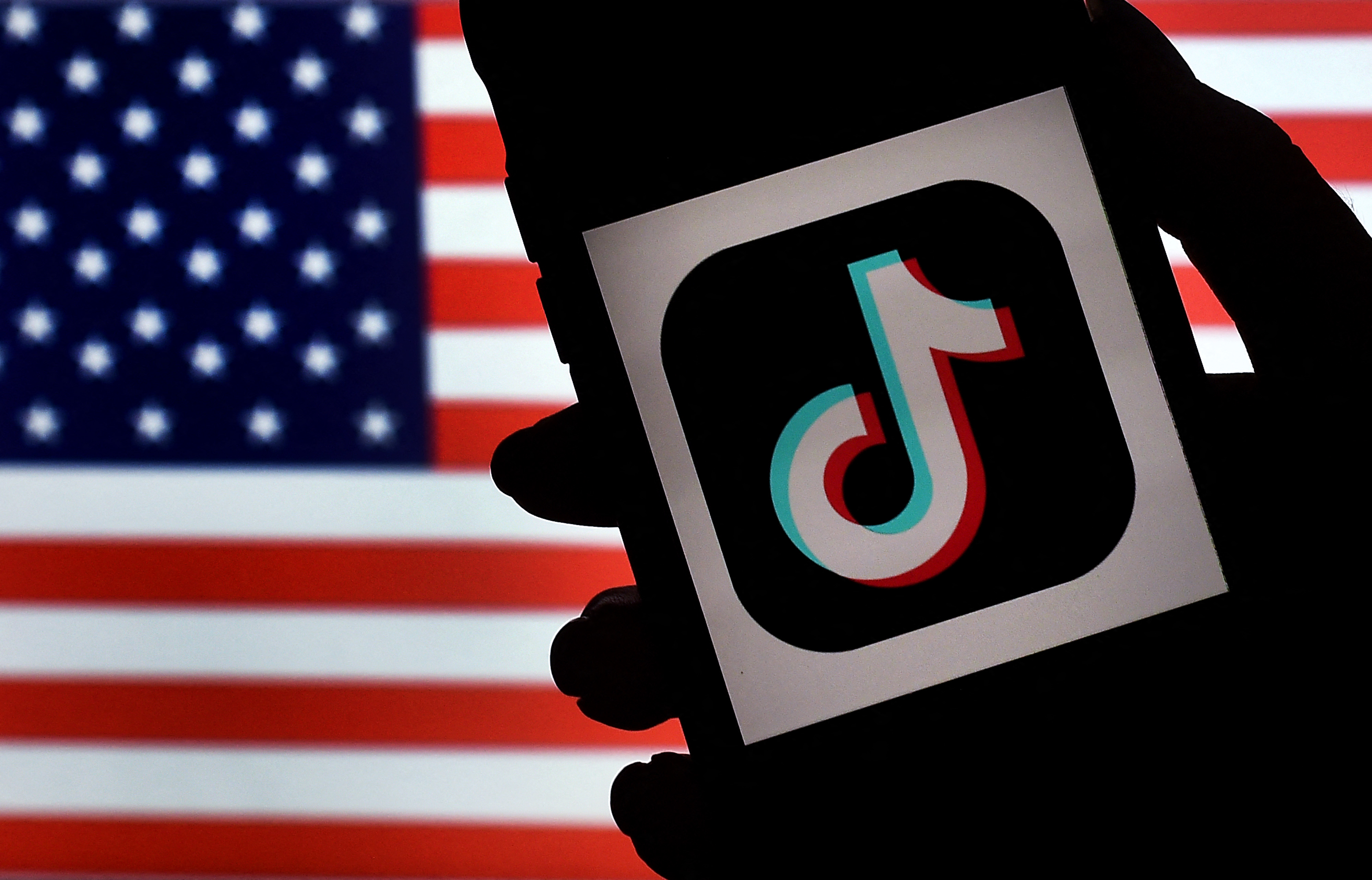 In this photo illustration, the social media application logo, TikTok is displayed on the screen of an iPhone on an American flag background on August 3, 2020 in Arlington, Virginia. - The US Senate voted on August 6, 2020, to bar TikTok from being downloaded onto US government employees' telephones, intensifying US scrutiny of the popular Chinese-owned video app. The bill passed by the Republican controlled Senate now goes to the House of Representatives, led by Democrats. (Photo by Olivier DOULIERY / AFP) (Photo by OLIVIER DOULIERY/AFP via Getty Images)