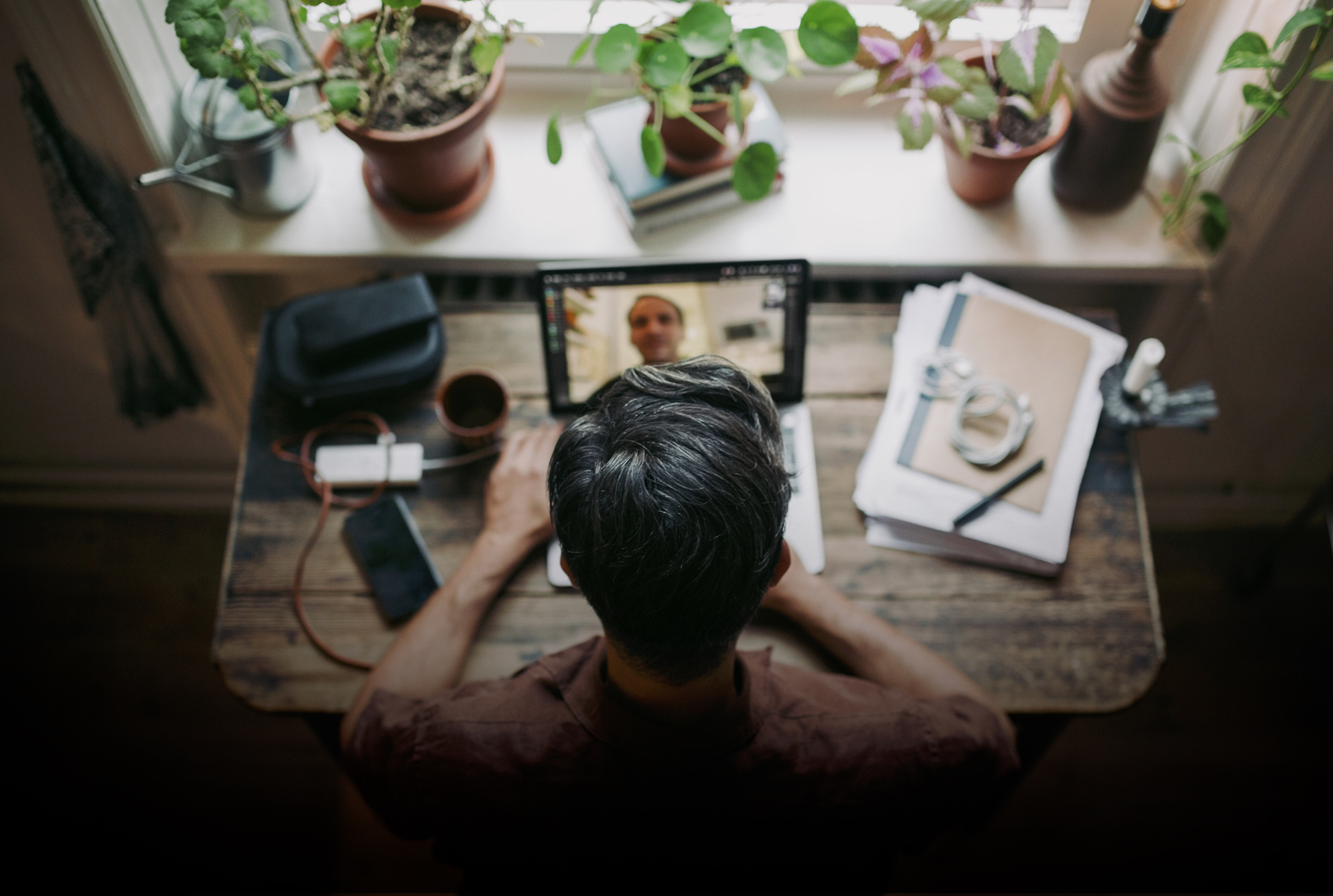 a photo from above looking at a person stood up at a desk on a video call