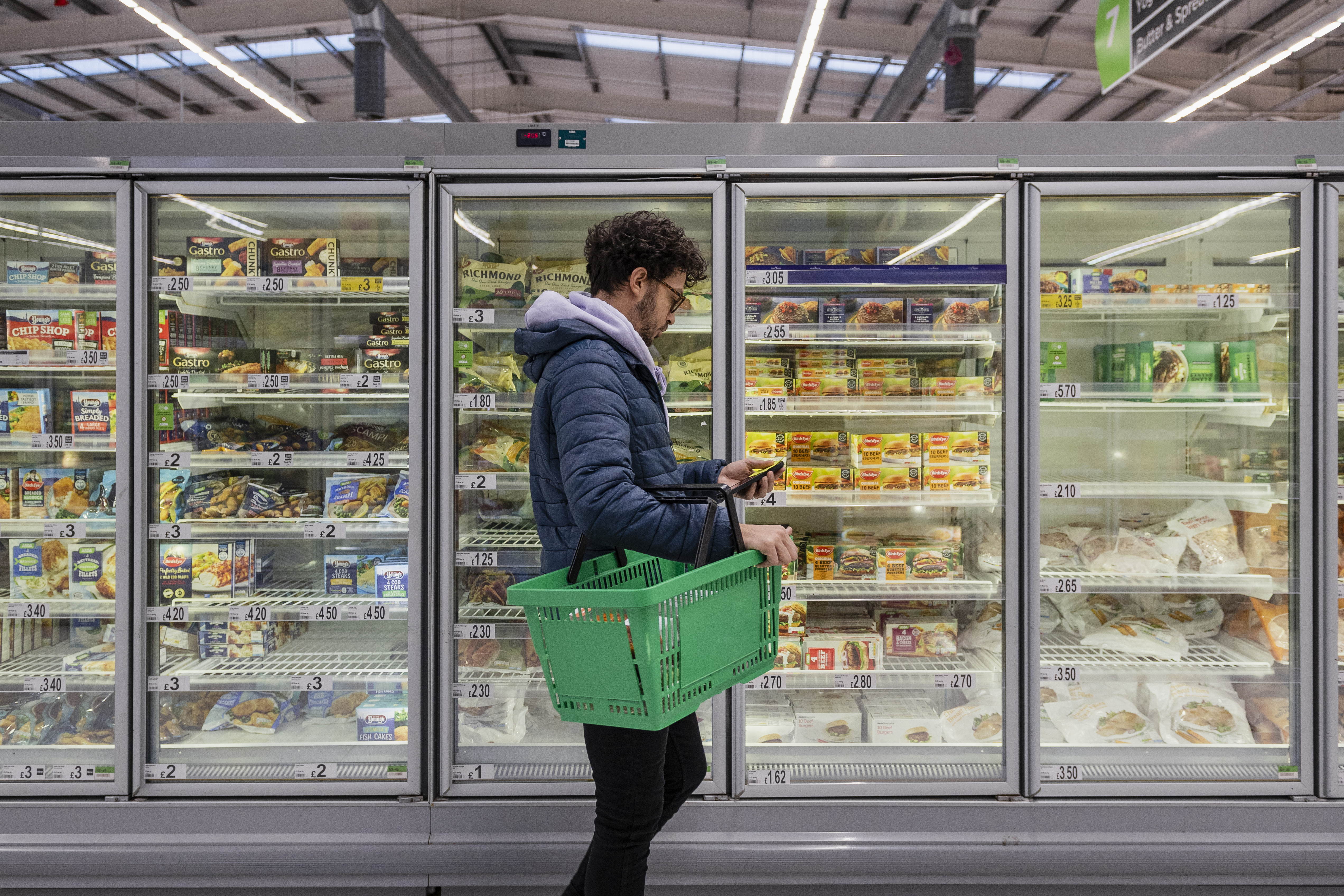 Man standing in front of refrigerator cases at a supermarket.