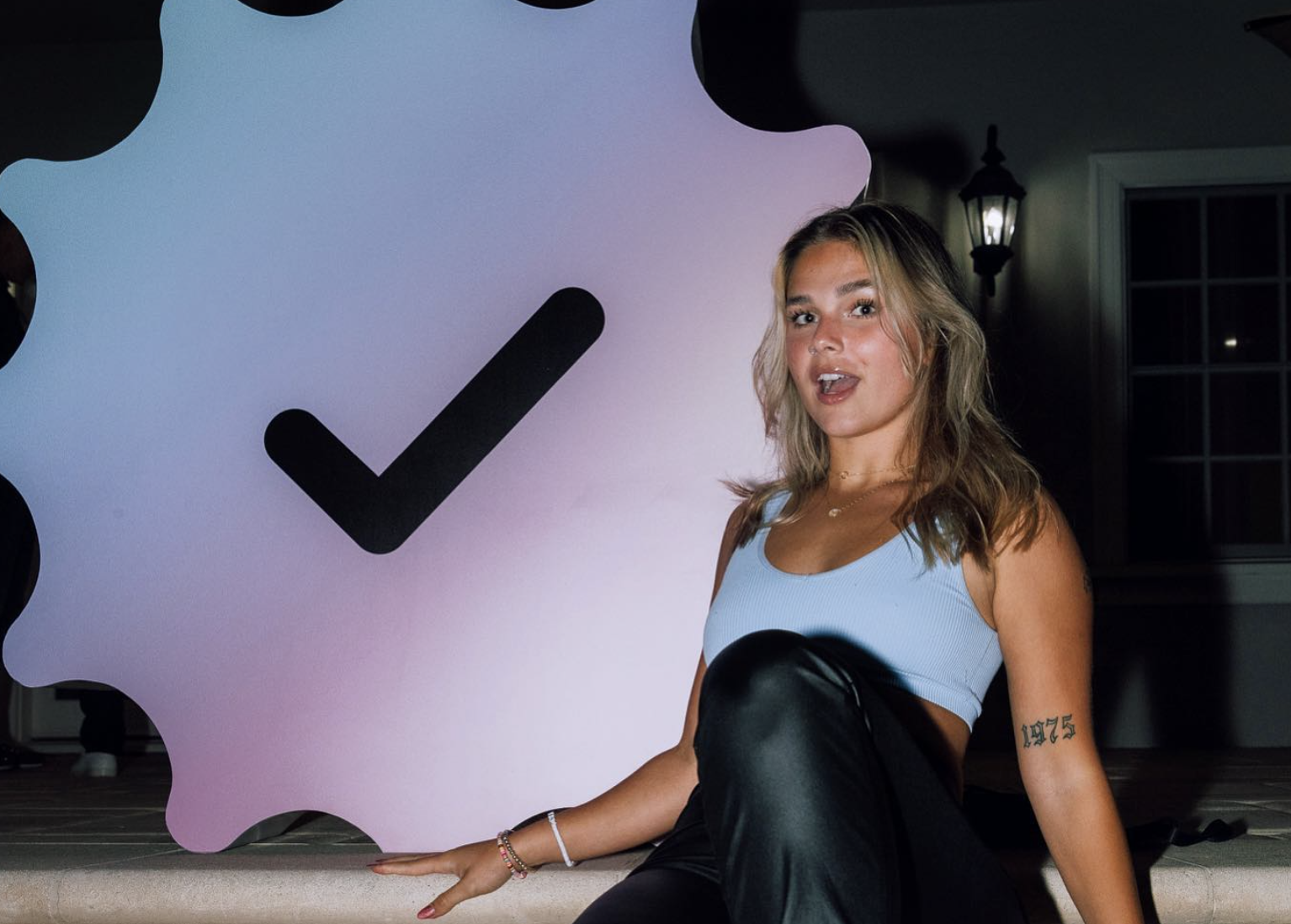 Fanfix; young woman standing in front of large checkmark