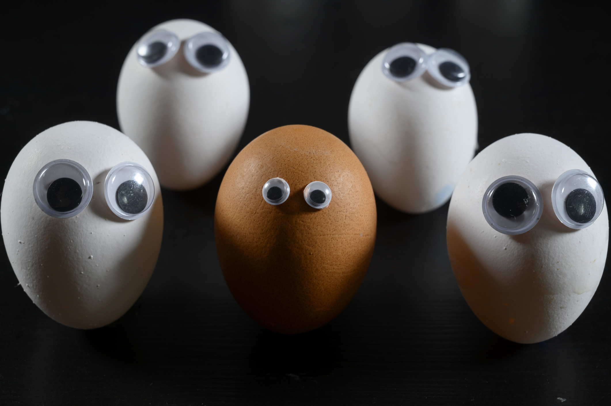 Brown face represented with an egg surrounded of white persons / eggs. Racism concept