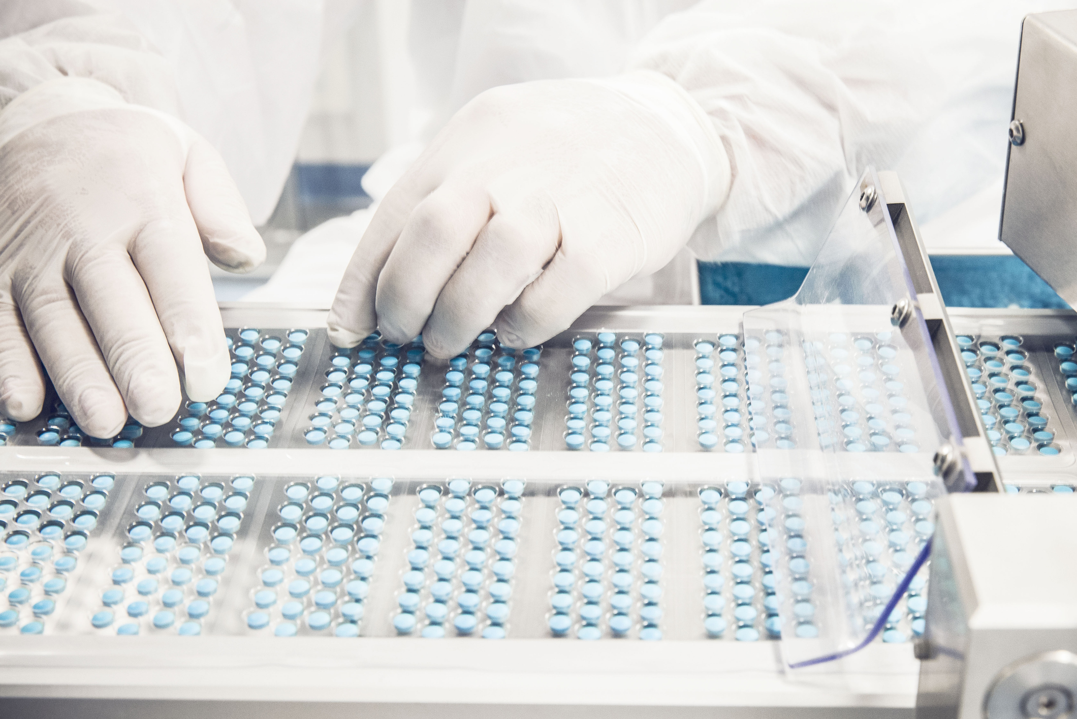 Worker inspecting pills on blisterpack conveyer belt