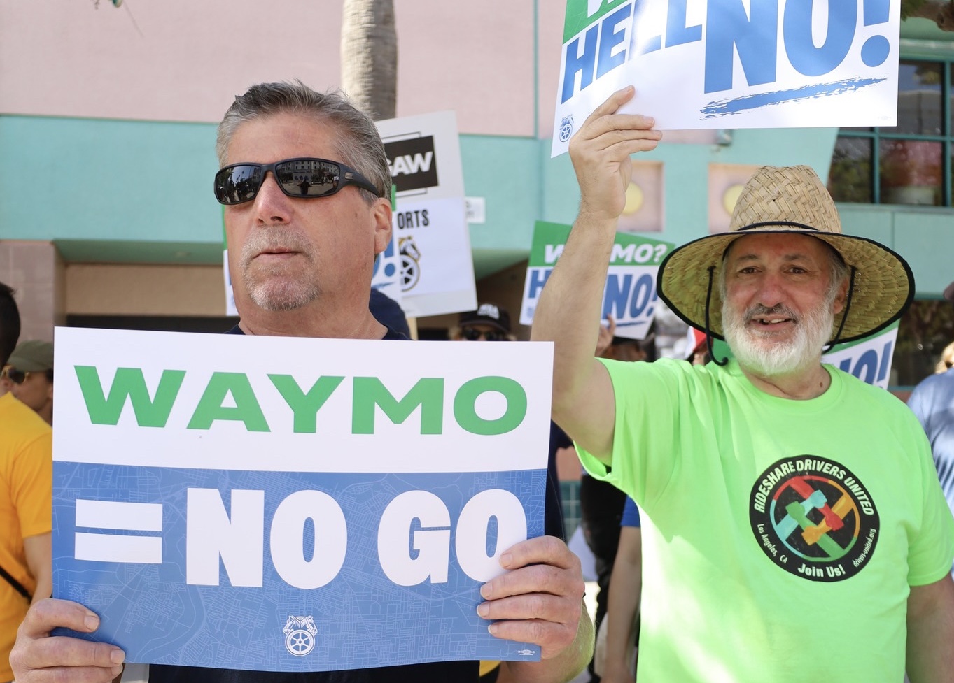 Men holding signs that say WAYMO = NO GO in all caps.
