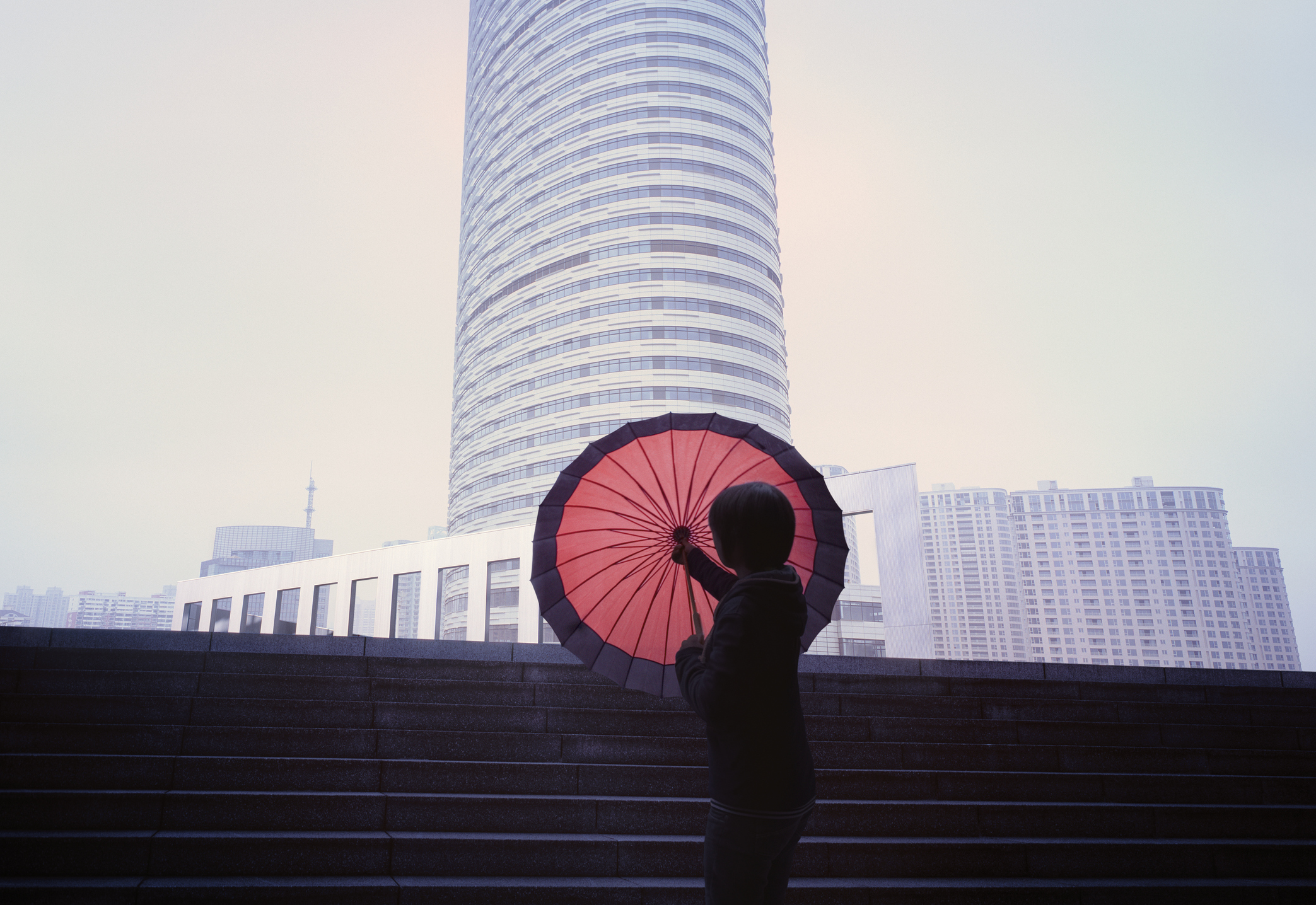 Women with red umbrella in front of city skyline