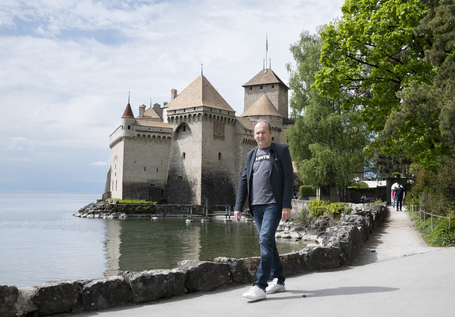 Man walking lakeside, castle in background