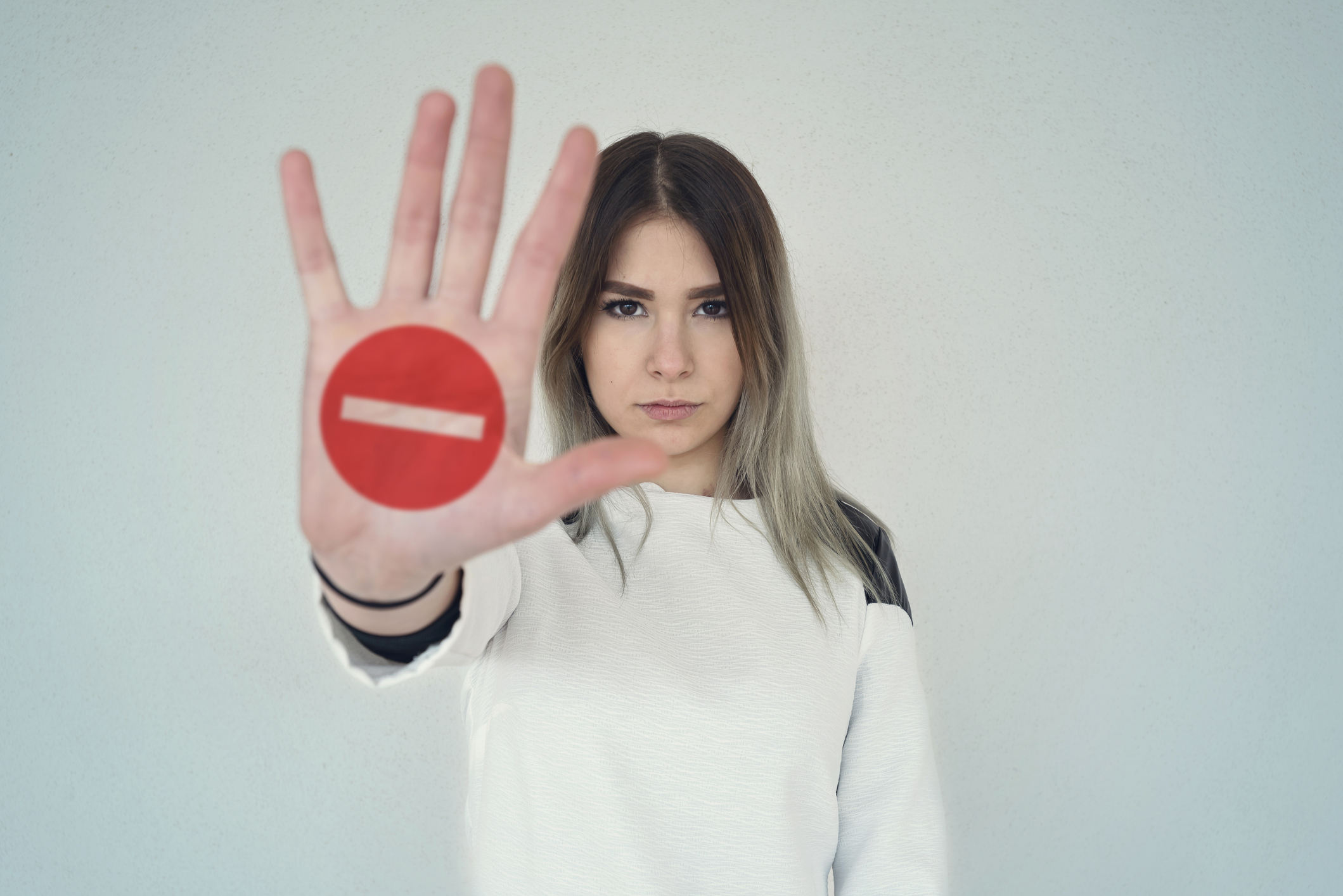 Woman holding hand out with stop sign on it.