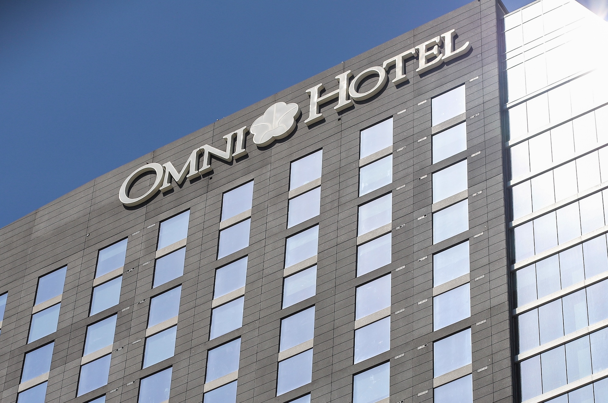 a photo outside of an Omni Hotel looking up at the building facade, with a blue sky