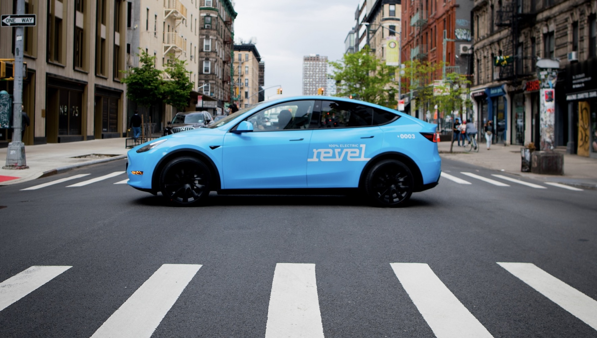 Light blue Revel rideshare mid-street