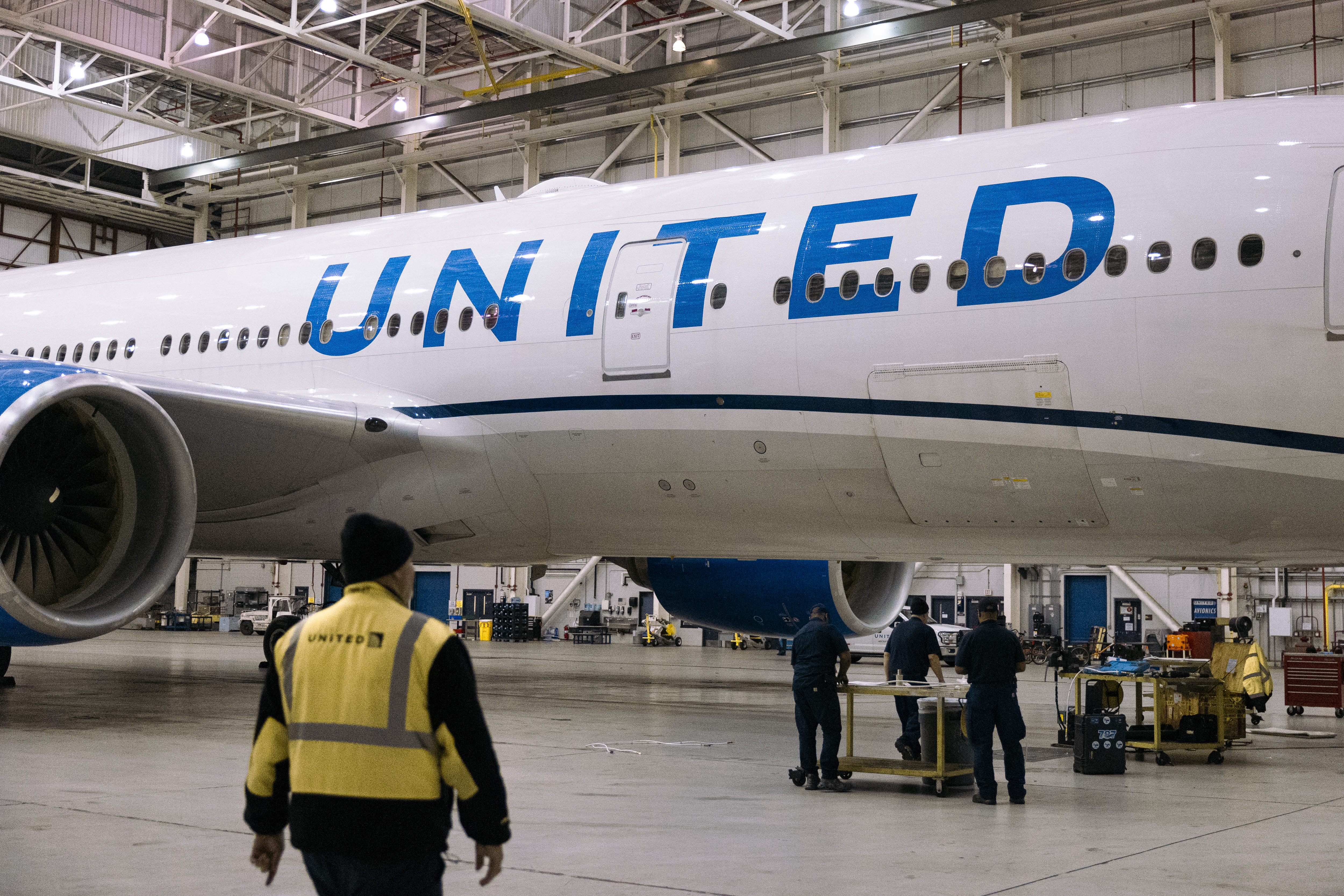 Workers replace an electrical cable on a Boeing 777-200 airplane in a United Airlines maintenance hangar at Newark Liberty International Airport in Newark, New Jersey.