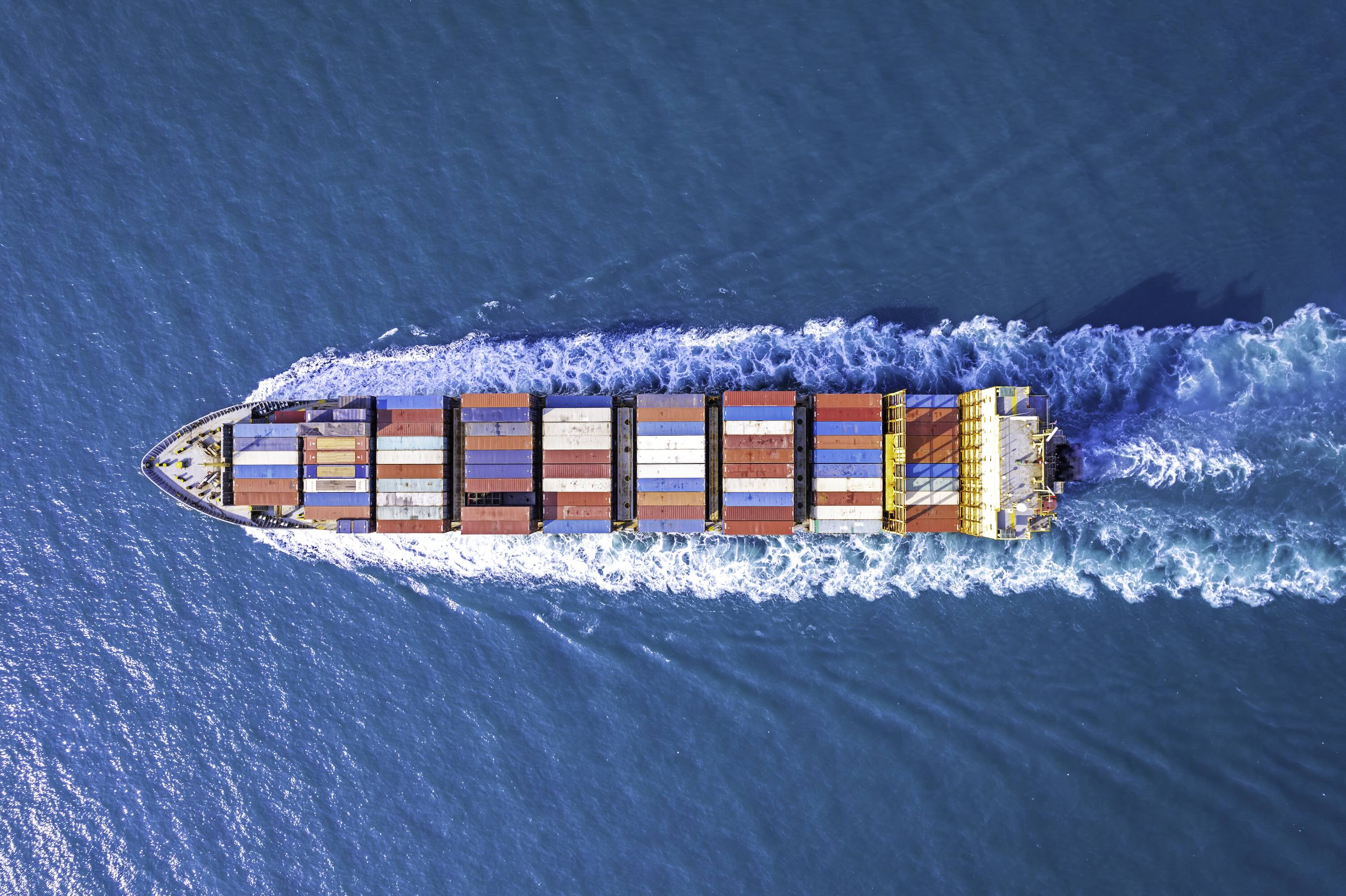 overhead shot as cargo ship sails on a blue sea.