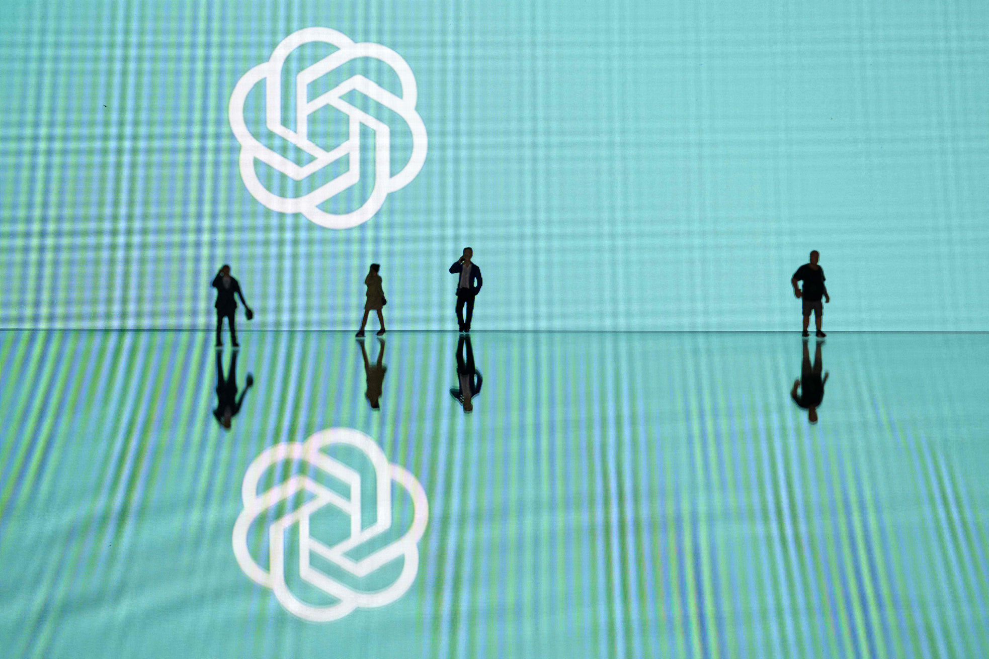 This photograph taken in Mulhouse, eastern France on October 19, 2023, shows figurines next to the ChatGPT logo. (Photo by SEBASTIEN BOZON/AFP via Getty Images)