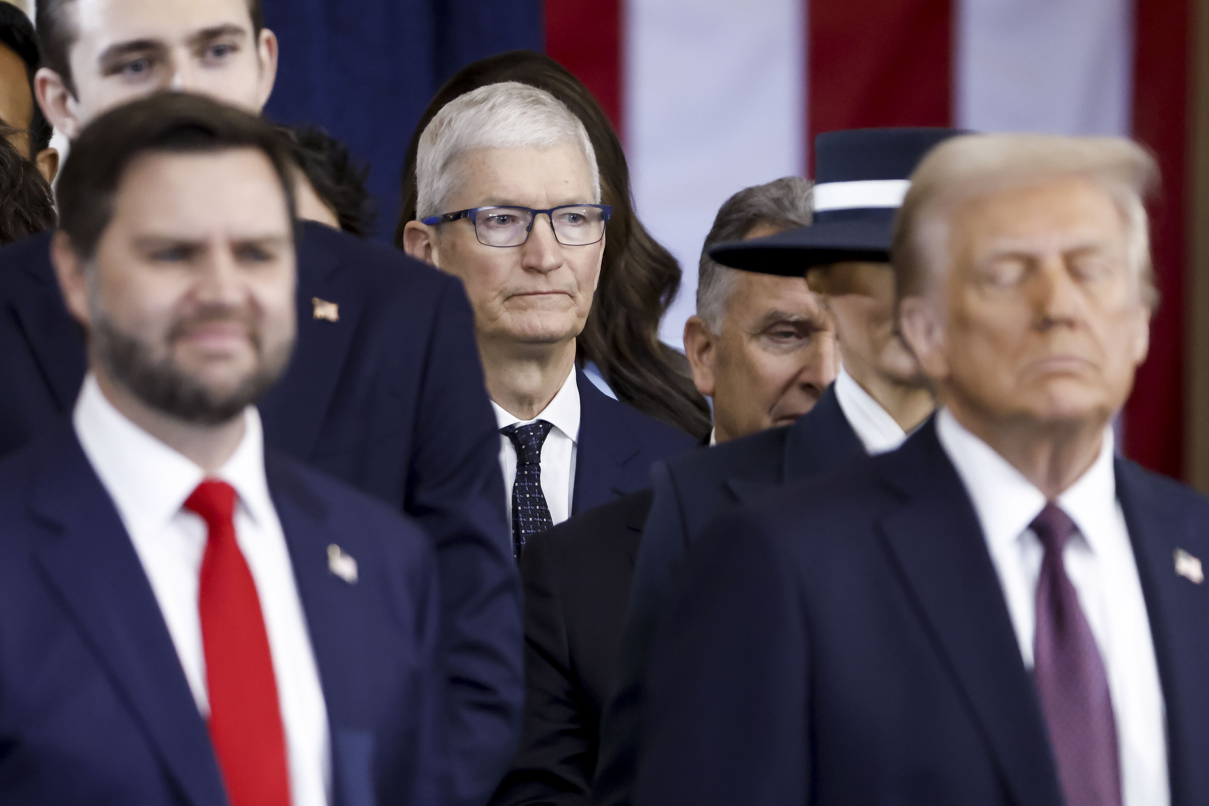 Apple CEO Tim Cook (C) seen behind US President Donald Trump (R) and US Vice President JD Vance (L) after the two were sworn into office at an inauguration ceremony in the rotunda of the United States Capitol on January 20, 2025 in Washington, DC.