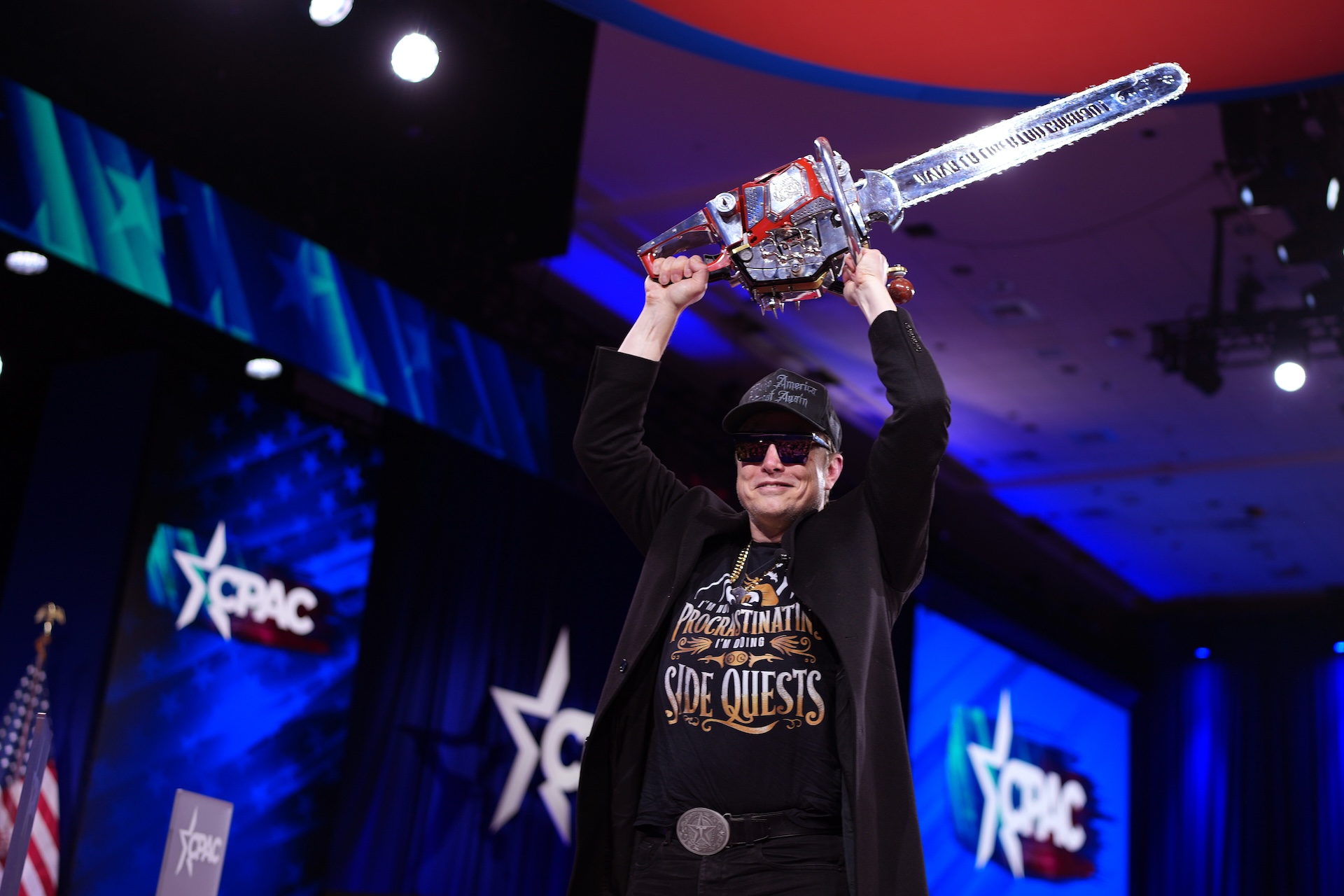 CEO of Tesla and SpaceX Elon Musk holding a chainsaw above his head.