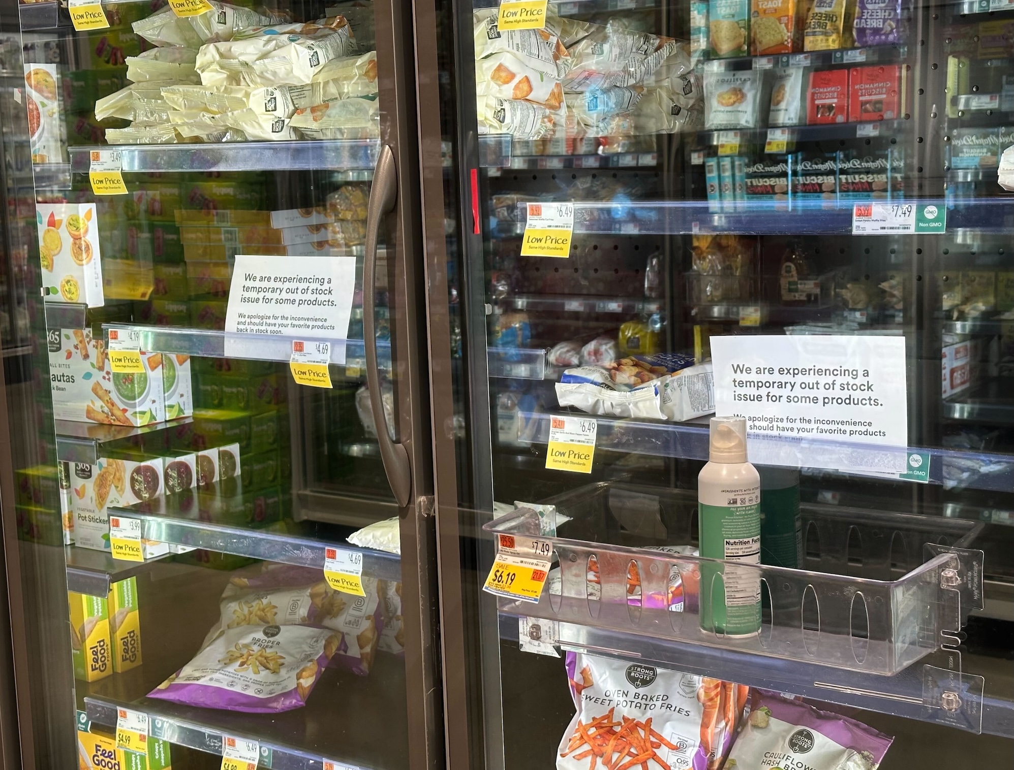 a photo of the frozen and refrigerated section at a local Whole Foods, with empty spaces, and signs warning of an out-of-stock issue.