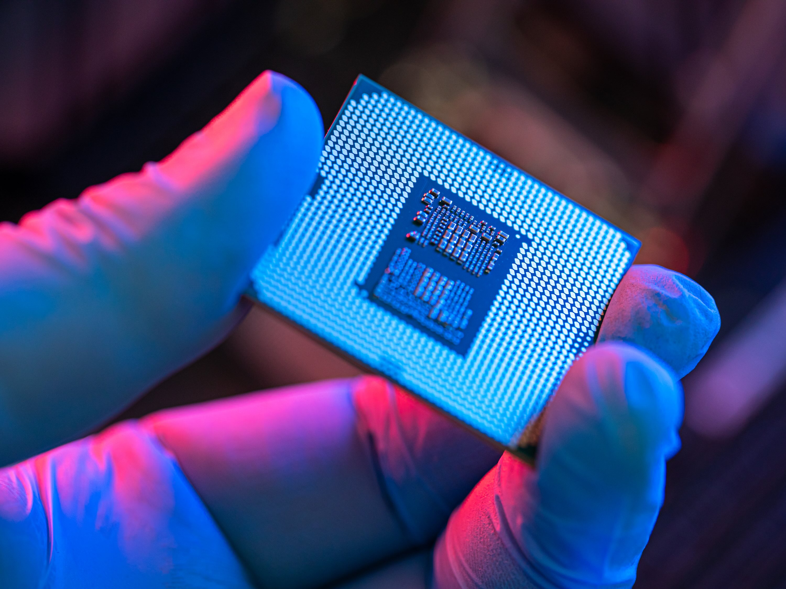 A gloved hand holds a computer chip.