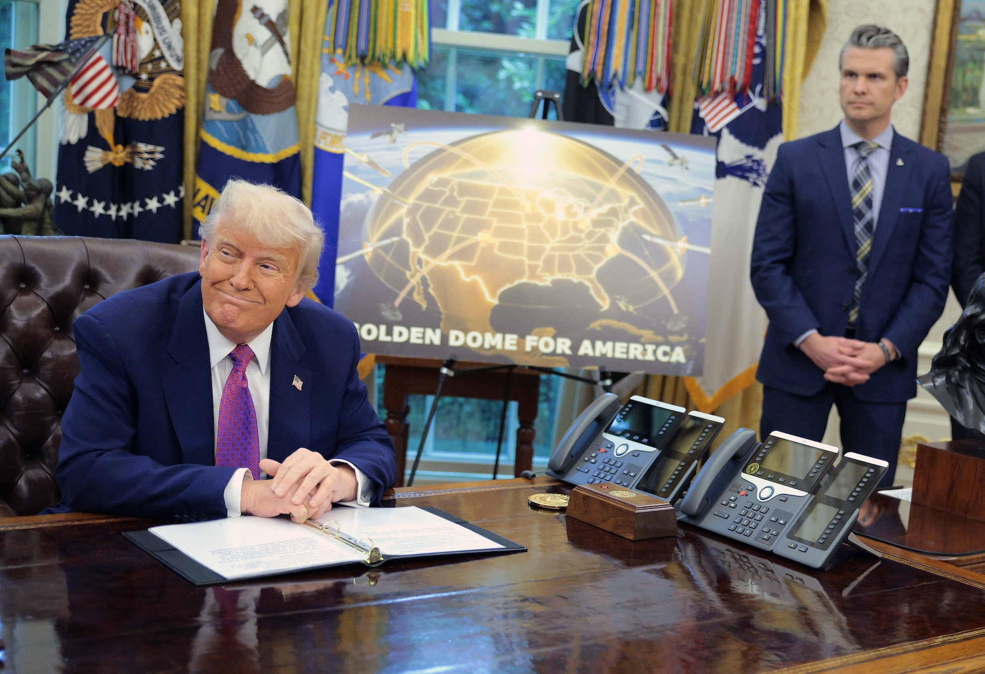 Golden Dome missile program placard with Trump sitting at desk