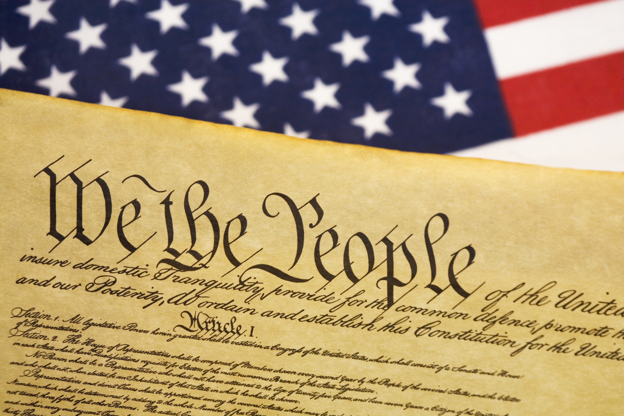 a photo of the US Constitution next to a US flag