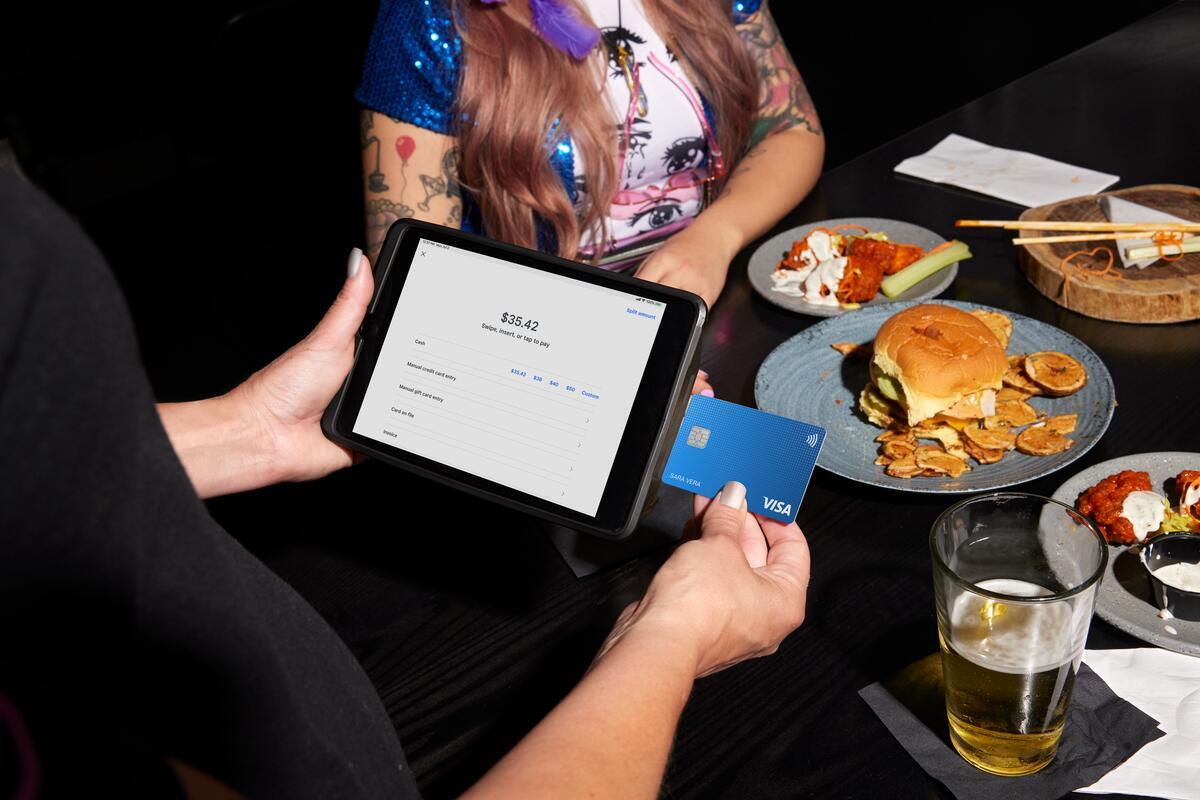 waiter using Square for credit card payment tableside at restaurant