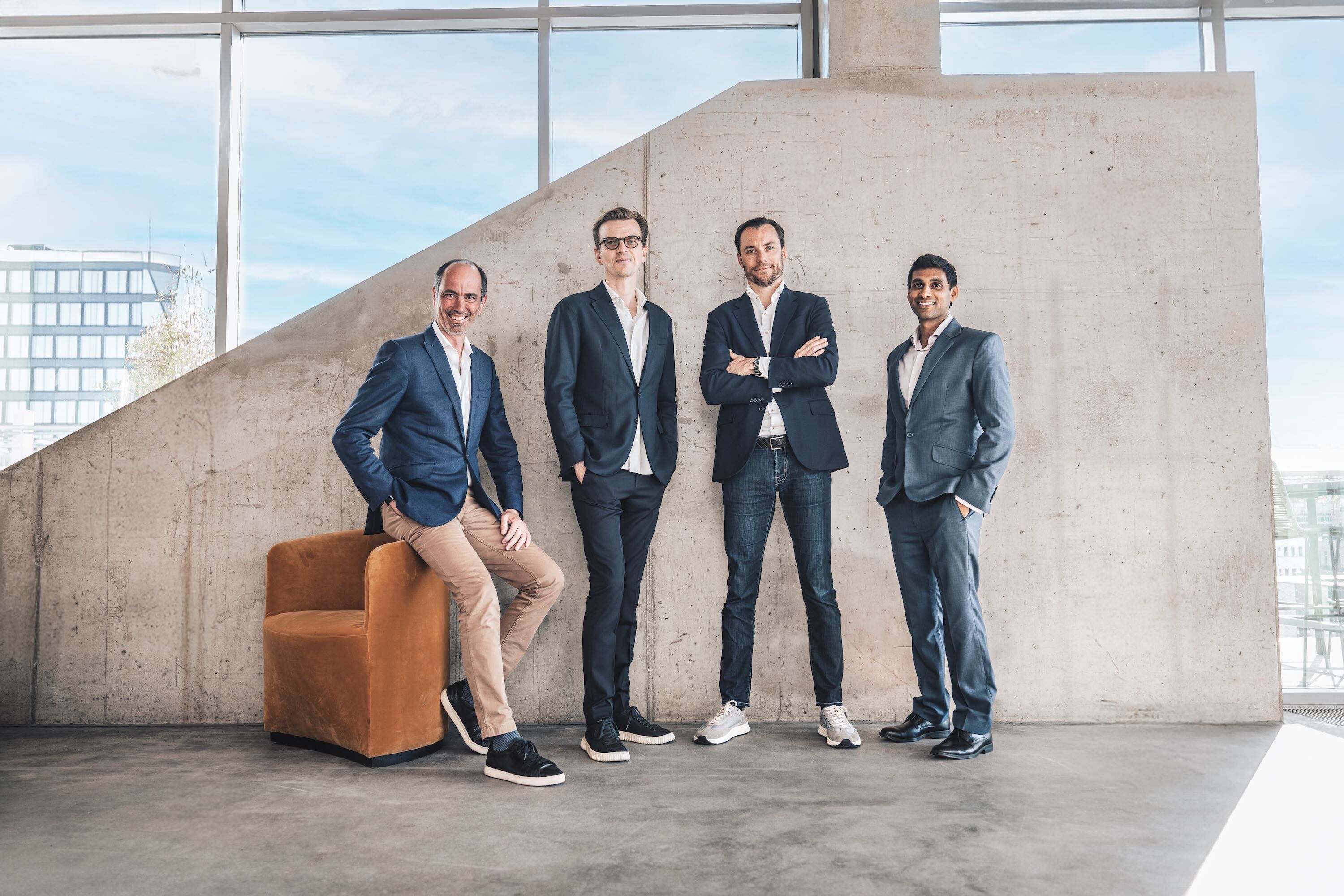 Four men standing in front of a concrete wall.