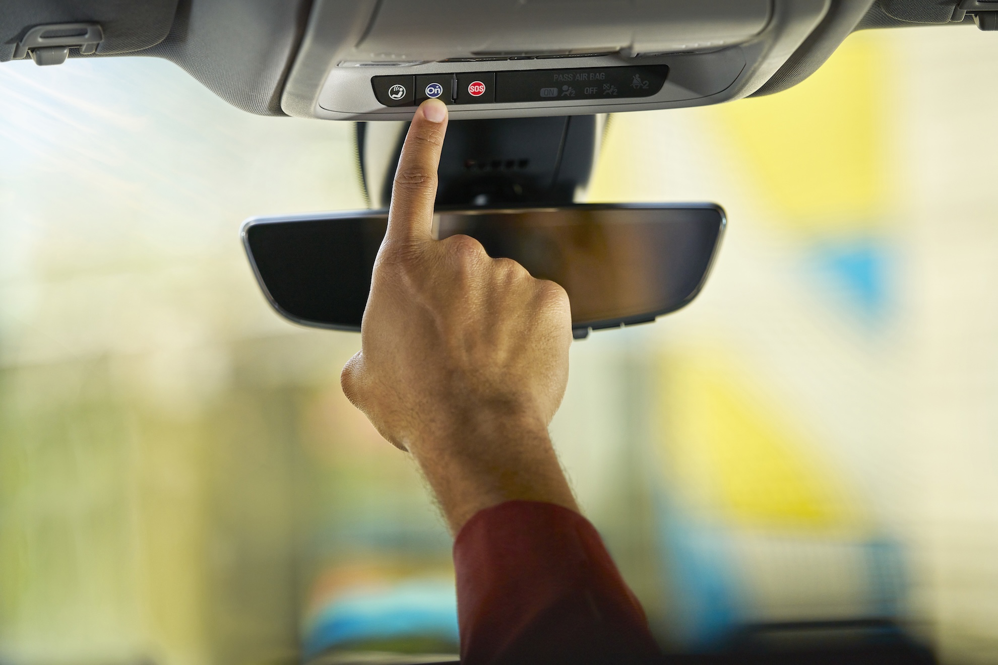 Person pushes the blue OnStar button in a GM vehicle.