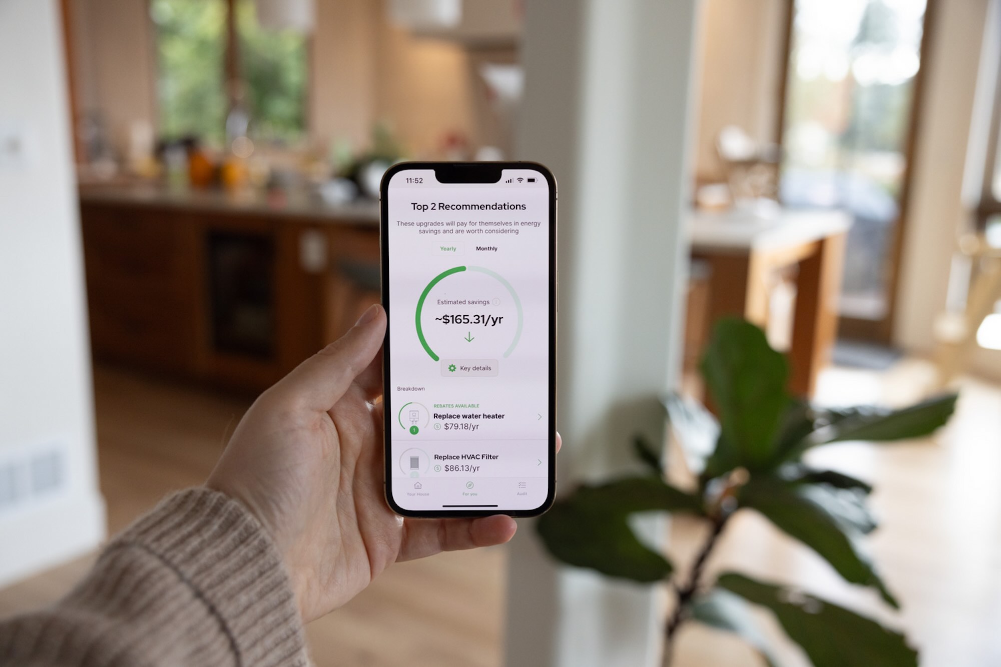 A person holds a phone showing an energy efficiency app.