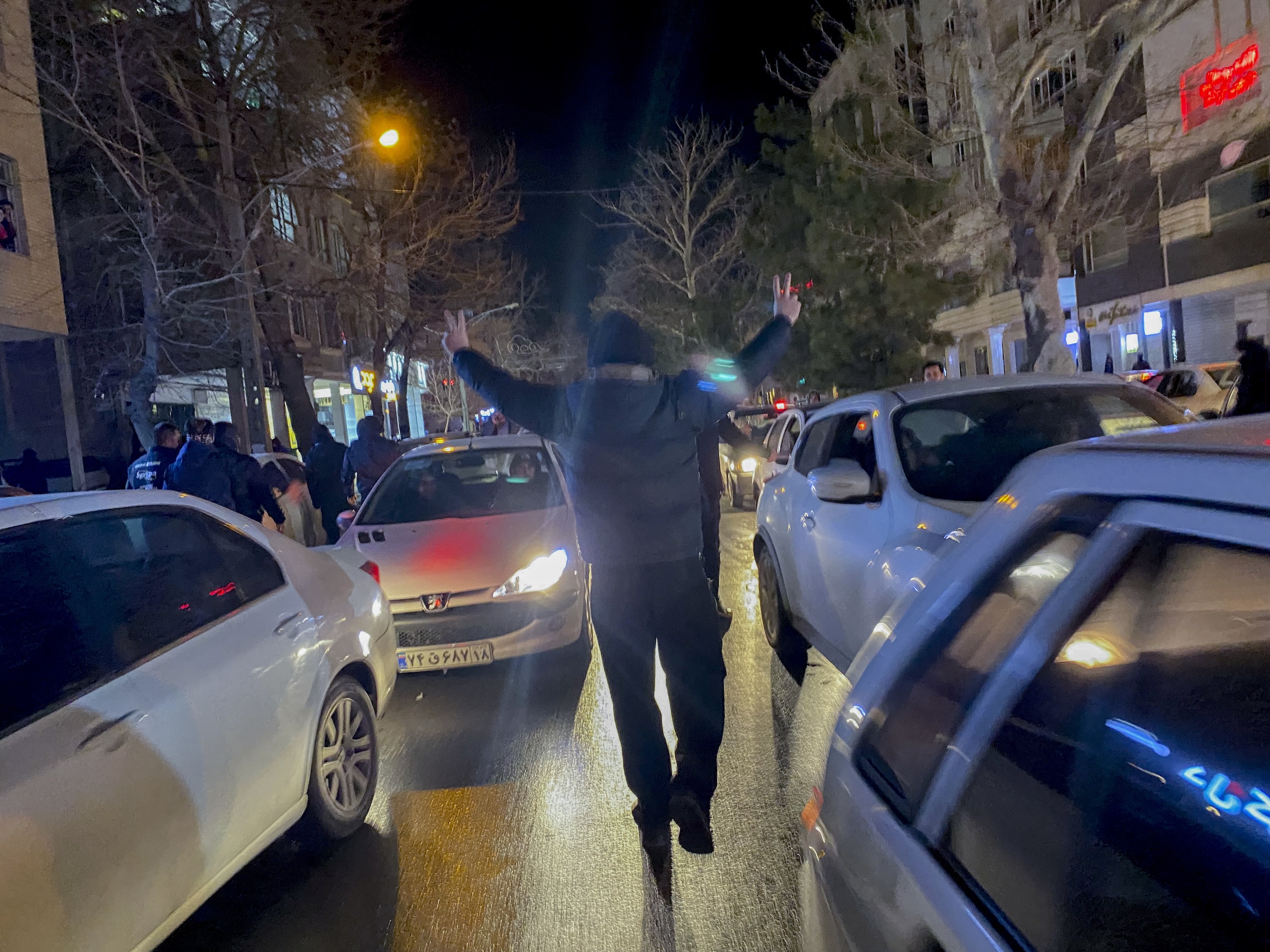 A protester flashes victory signs as traffic slows during demonstrations in Hamedan, Iran, on January 1, 2026.