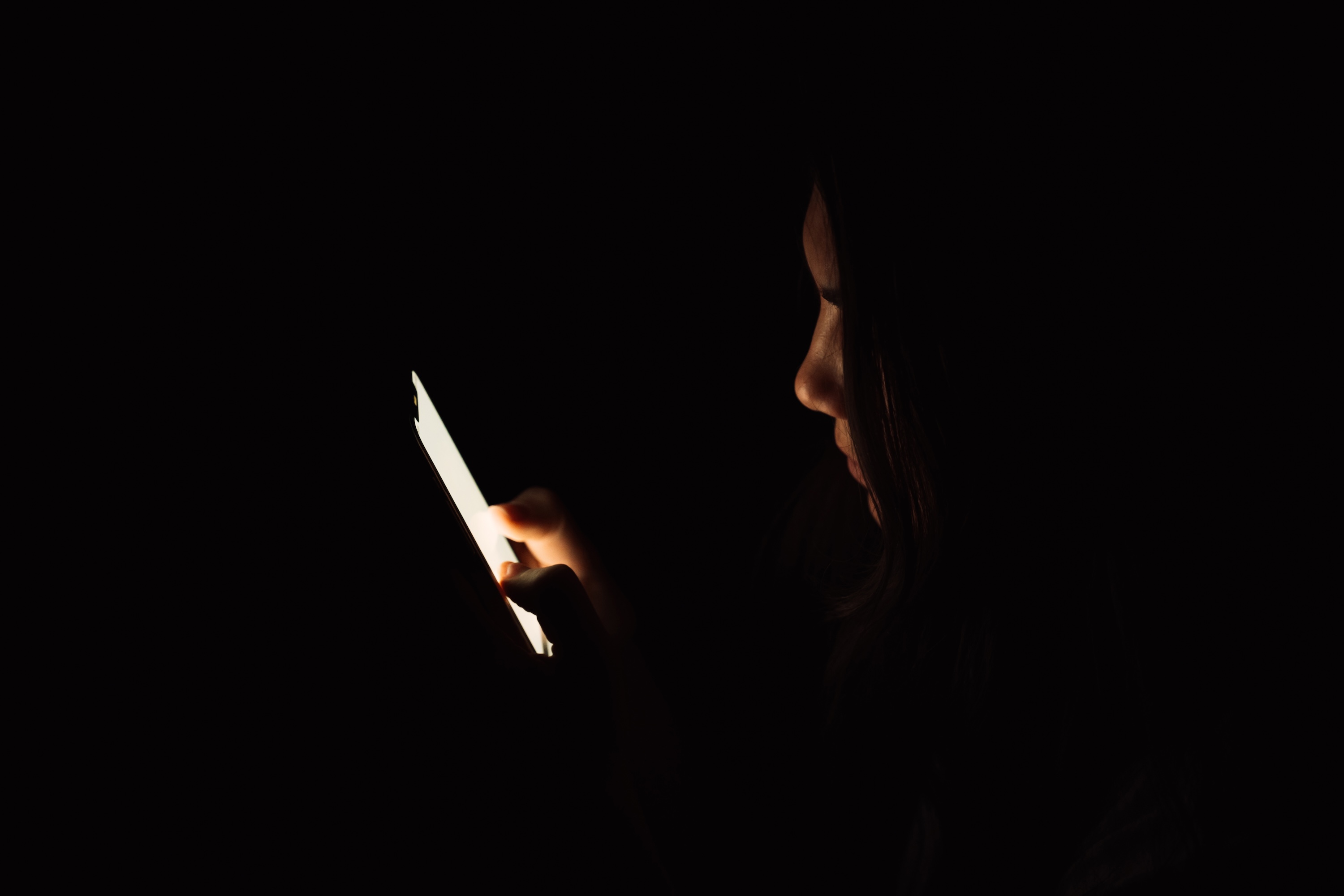 Lady looking at smartphone in dark room.